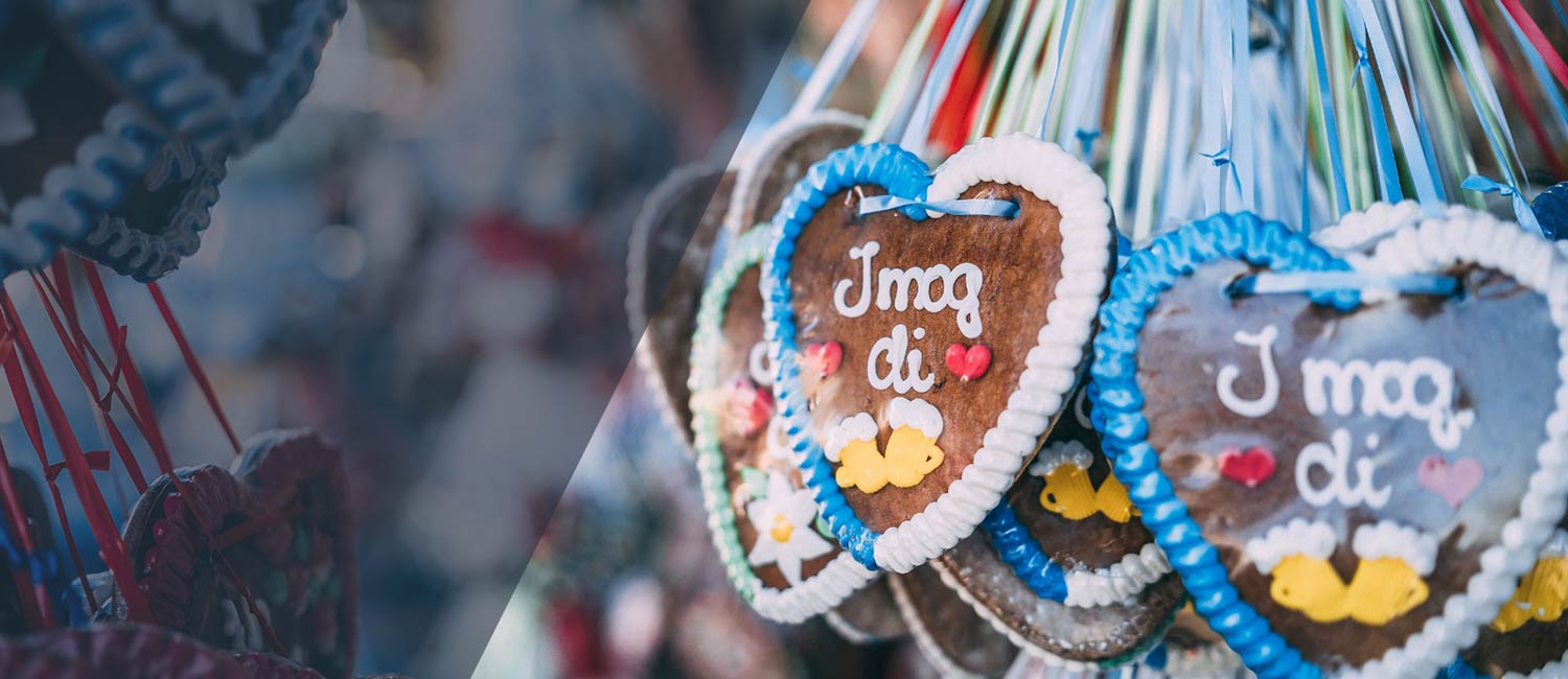 Reihe handgemachter Lebkuchenherzen mit blauer und weißer Zuckerglasur, Beschriftung "J mog di" & Bierkrugmotiven.