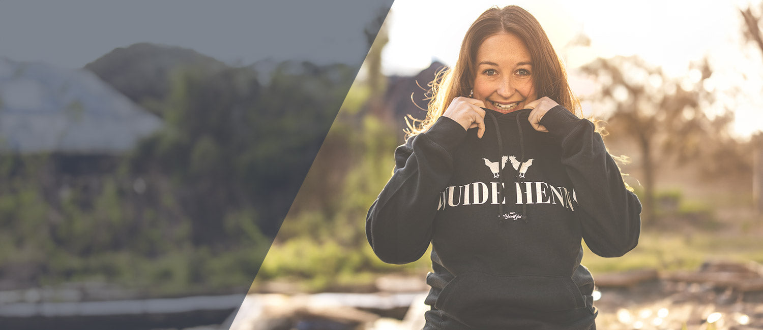 Lachende Frau in schwarzem bayerischen Hoodie mit "Guade Henna" Aufdruck.