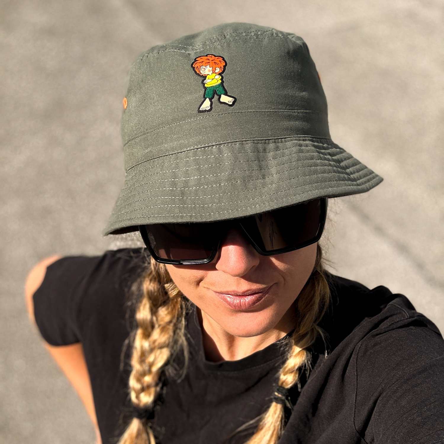 Frau trägt olivegrünen Fischerhut mit Pumuckl-Stick