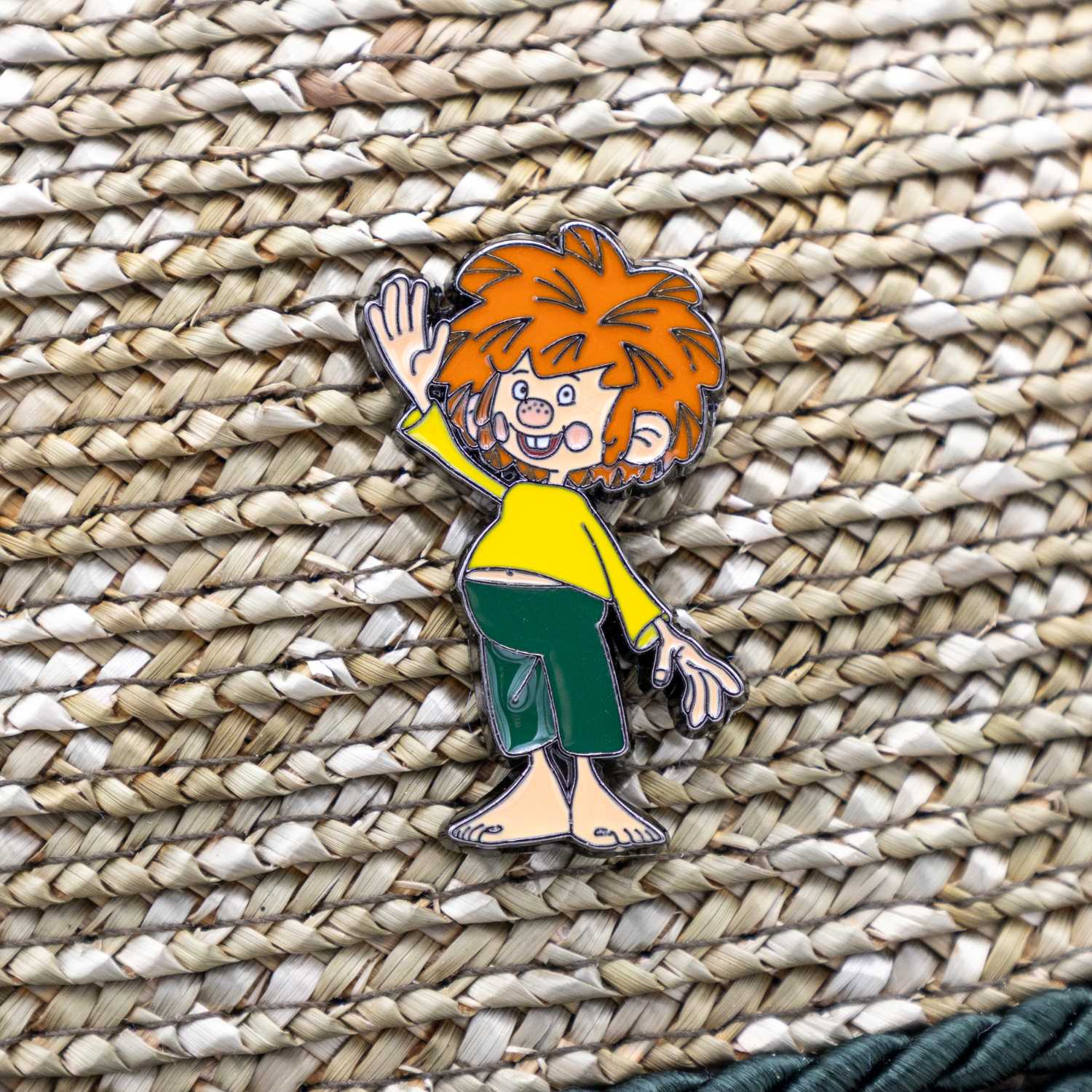 Detailansicht des Pumuckl-Servus-Pins am Strohhut – bunter Emaille-Anstecker mit fröhlichem Pumuckl auf gewebtem Untergrund