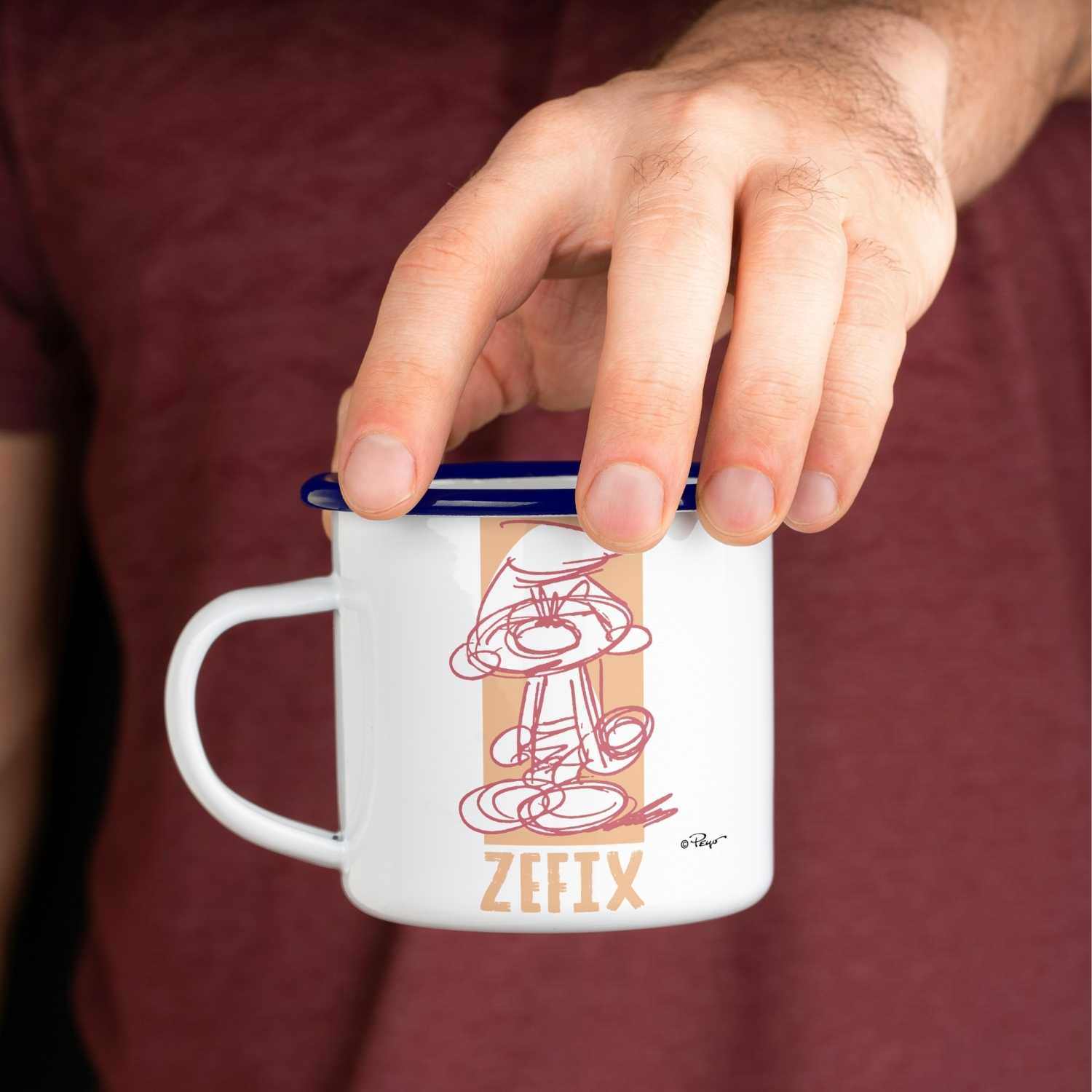 Emaille-Tasse mit blauem Rand, Schlumpf-Motiv und großem „ZEFIX!“-Schriftzug auf weißem Untergrund, Fassungsvermögen 330 ml.