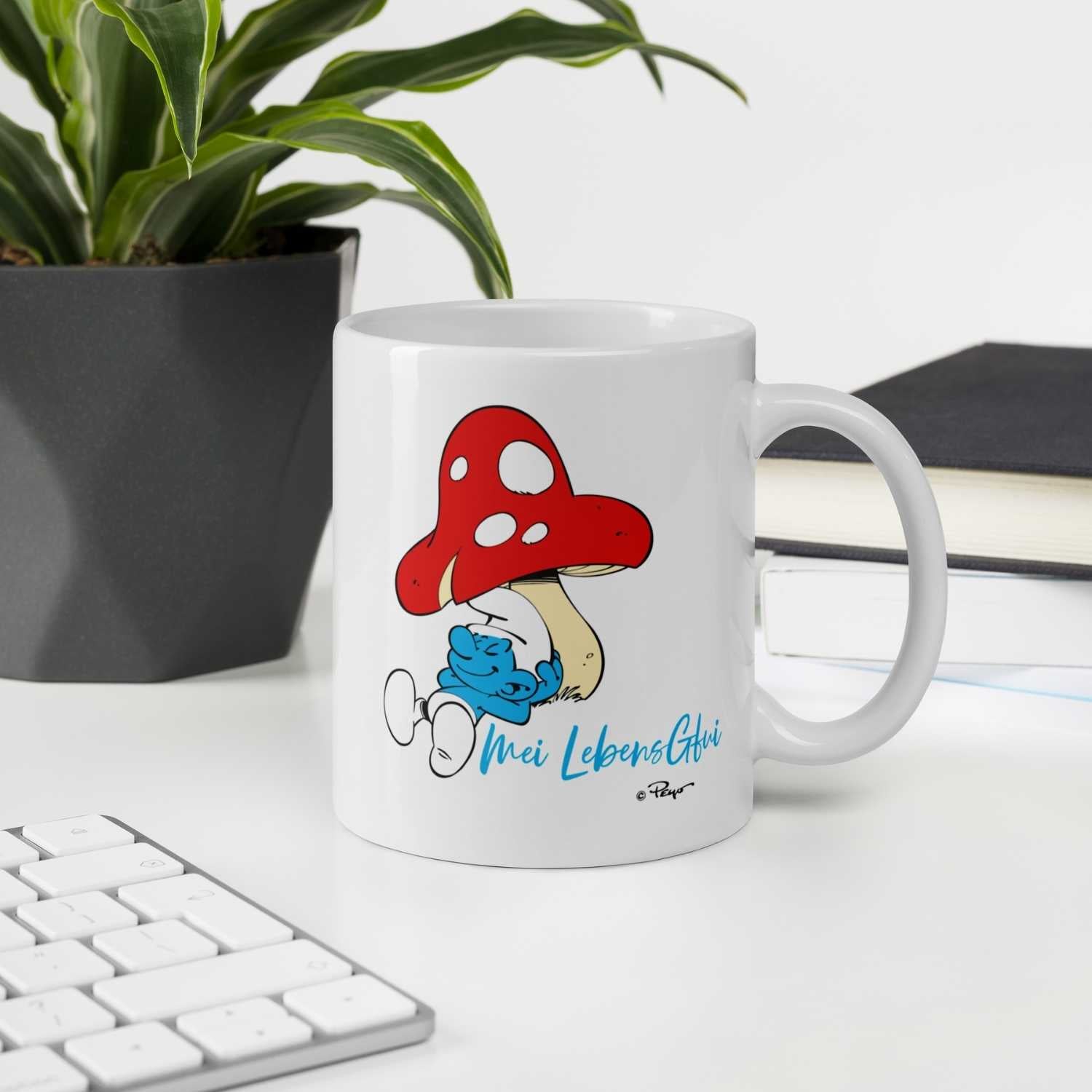 Weiße Porzellantasse mit farbigem Schlumpf-Motiv und bayerischem Schriftzug „Do legst di nieda“, 330 ml.