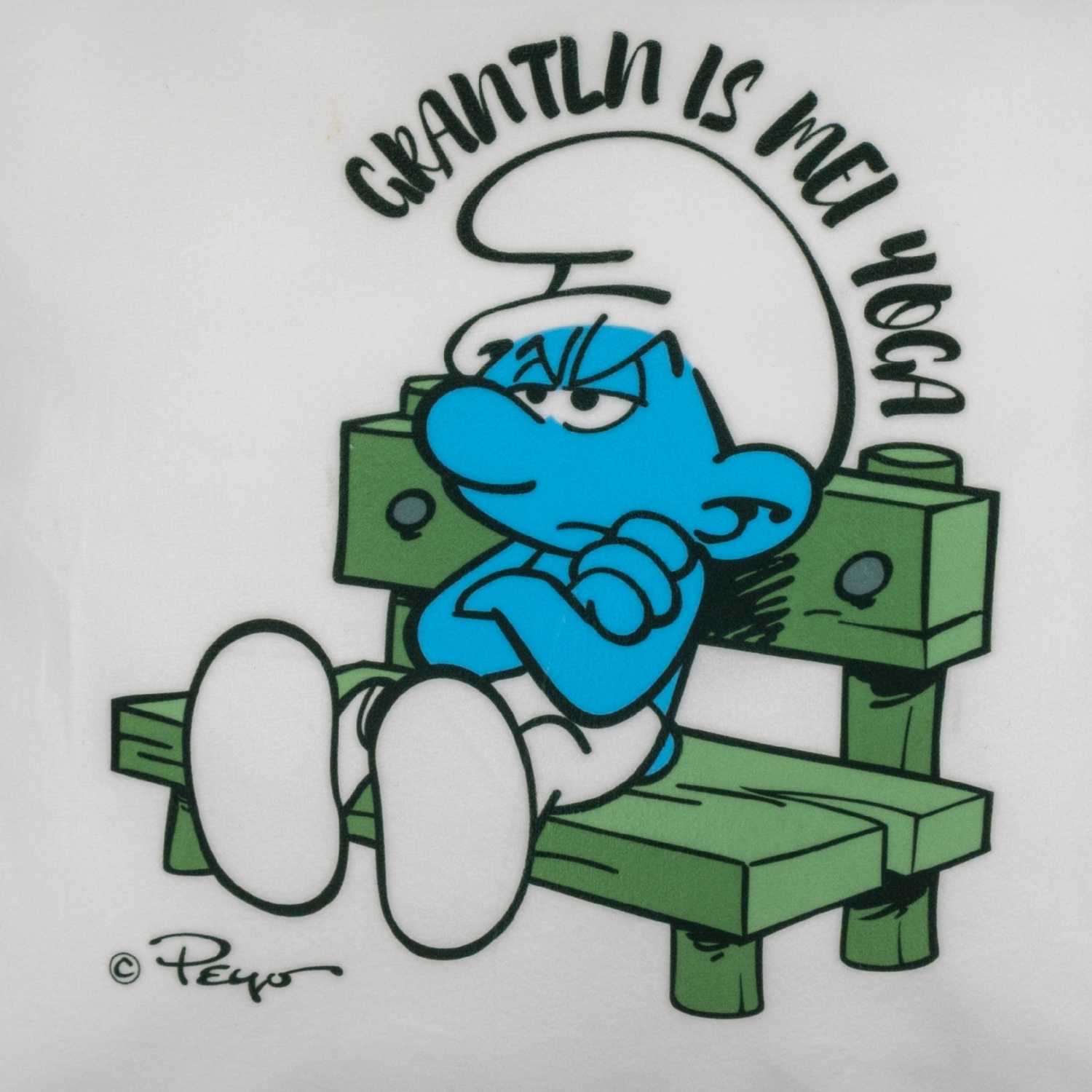 Quadratisches Deko-Kissen mit Schlumpf-Motiv und dem aufgedruckten Spruch „Grantln is mei Yoga“, weich gepolstert.