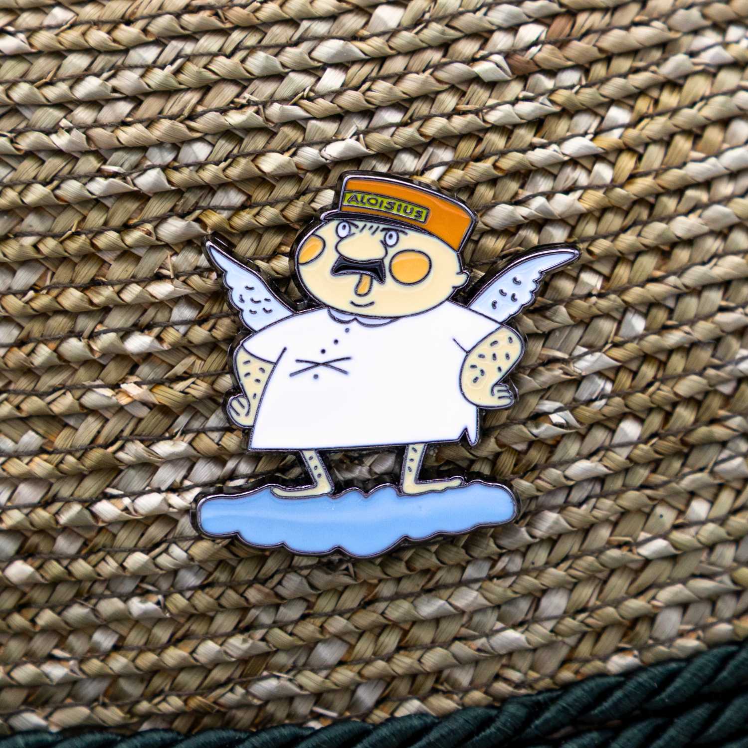 Detailaufnahme des Emaille-Pins Engel Aloisius "Luhja" auf geflochtenem Bast, humorvoller Bayern-Fanartikel.