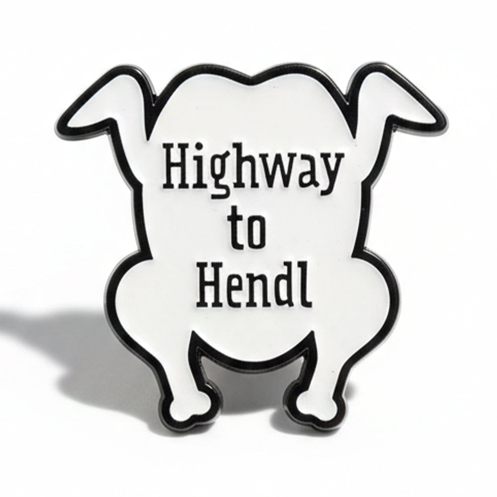 Schwarz-weißer Emaille-Pin in Hähnchenform mit lustigem Spruch Highway to Hendl für Fans bayerischer Küche.