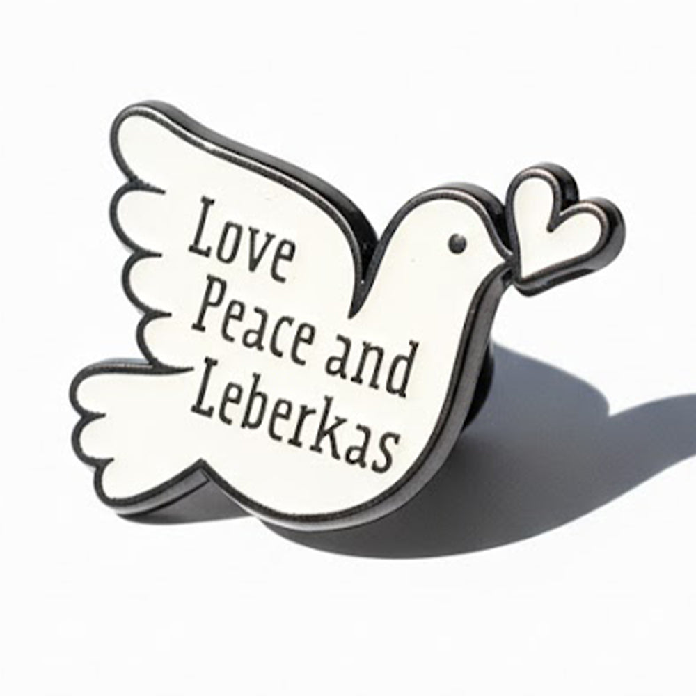 Schwarzer und weißer Tauben-Pin mit dem Schriftzug "Love, Peace and Leberkas" und kleinem Herz.