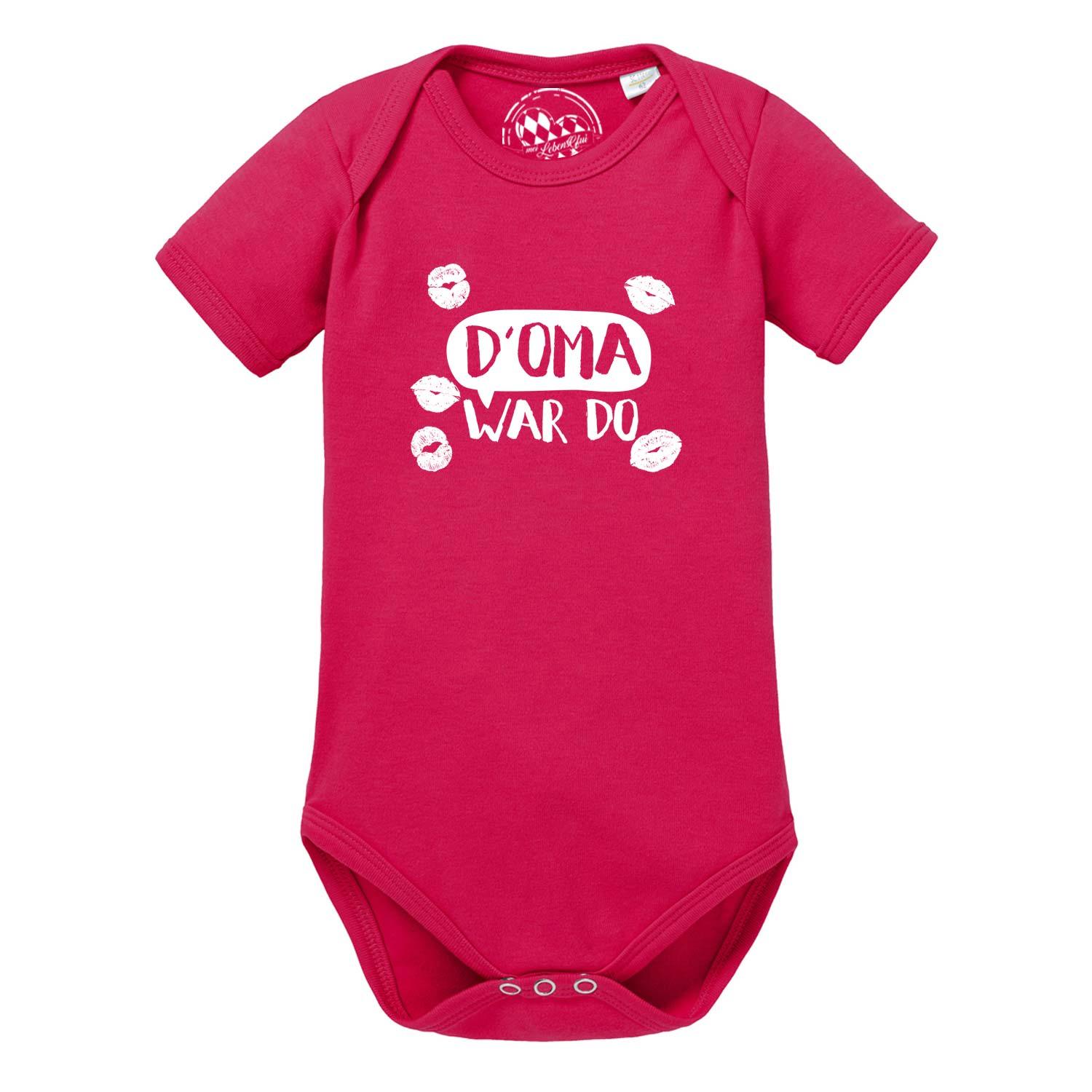Weißer Babybody mit kurzen Ärmeln, blauem Trachten-Motiv und Aufdruck „D’ Oma war do…“, aus Baumwolle.