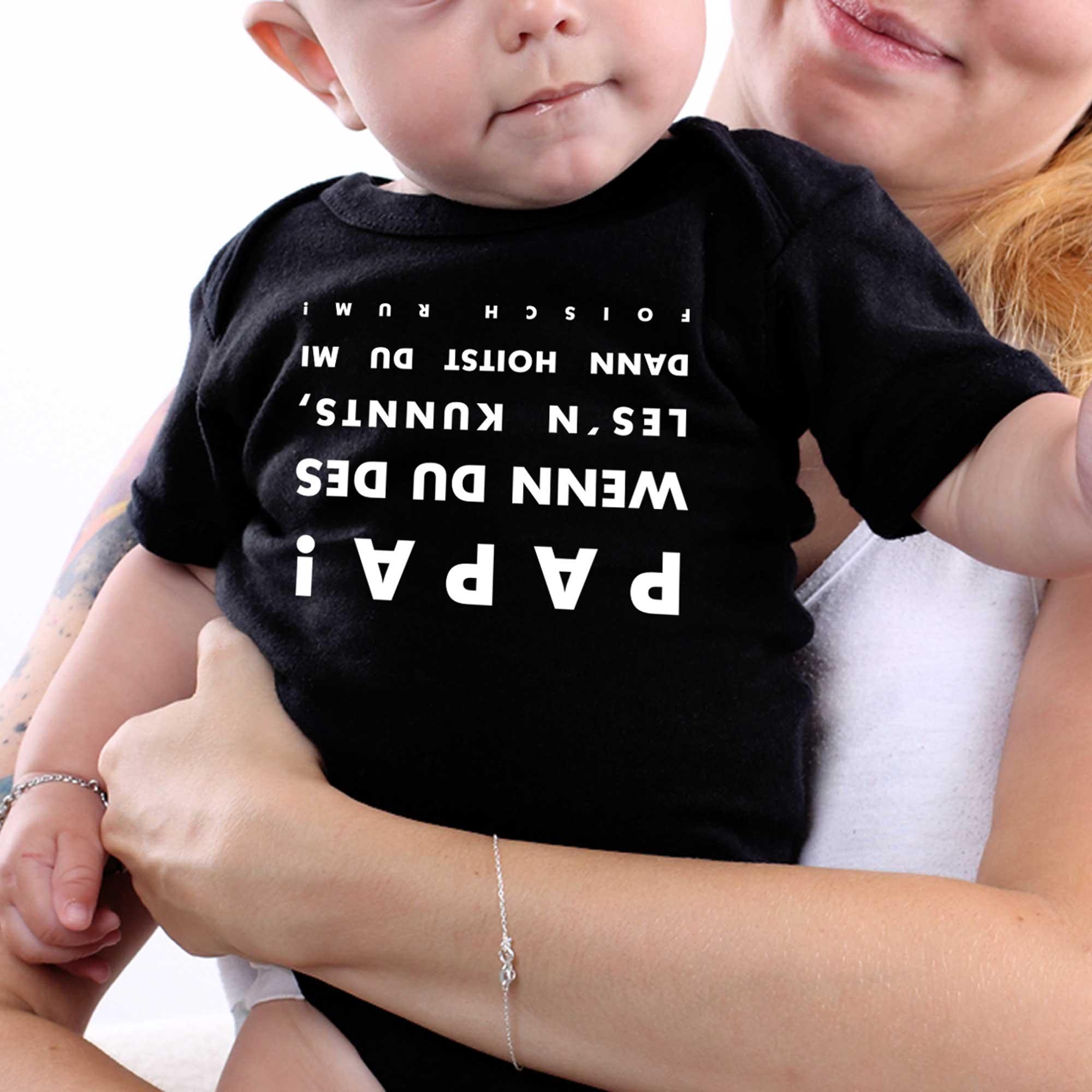 Kurzärmeliger Babybody in Weiß mit dunkelblauer Aufschrift „falsch rum“ und durchgekreuztem Pfeil; Baumwolle.