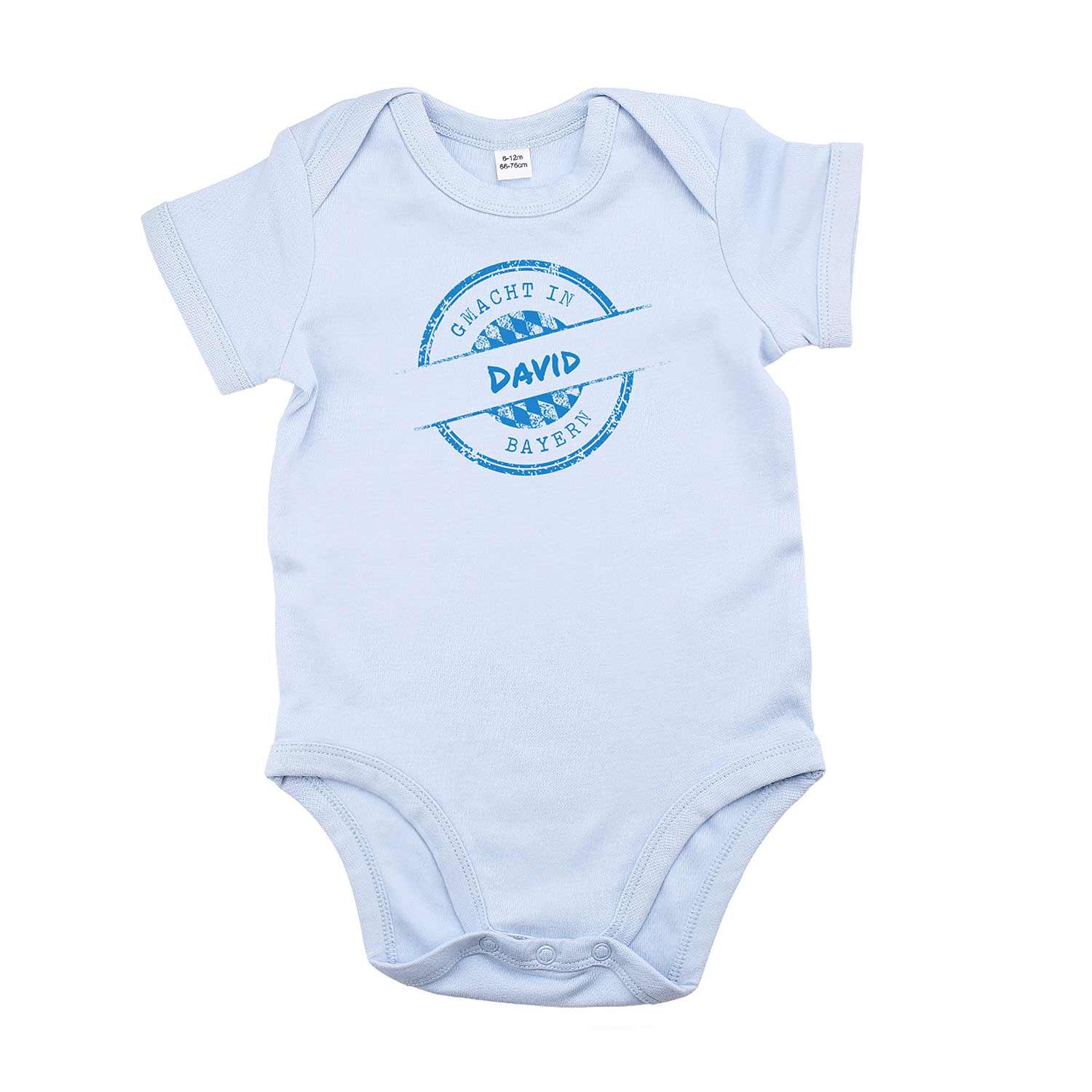 Blauer Baby-Body mit weißem Aufdruck „gmacht in Bayern“ und personalisierbarem Wunschnamen, kurze Ärmel, Druckknöpfe im Schritt, aus Baumwolle.