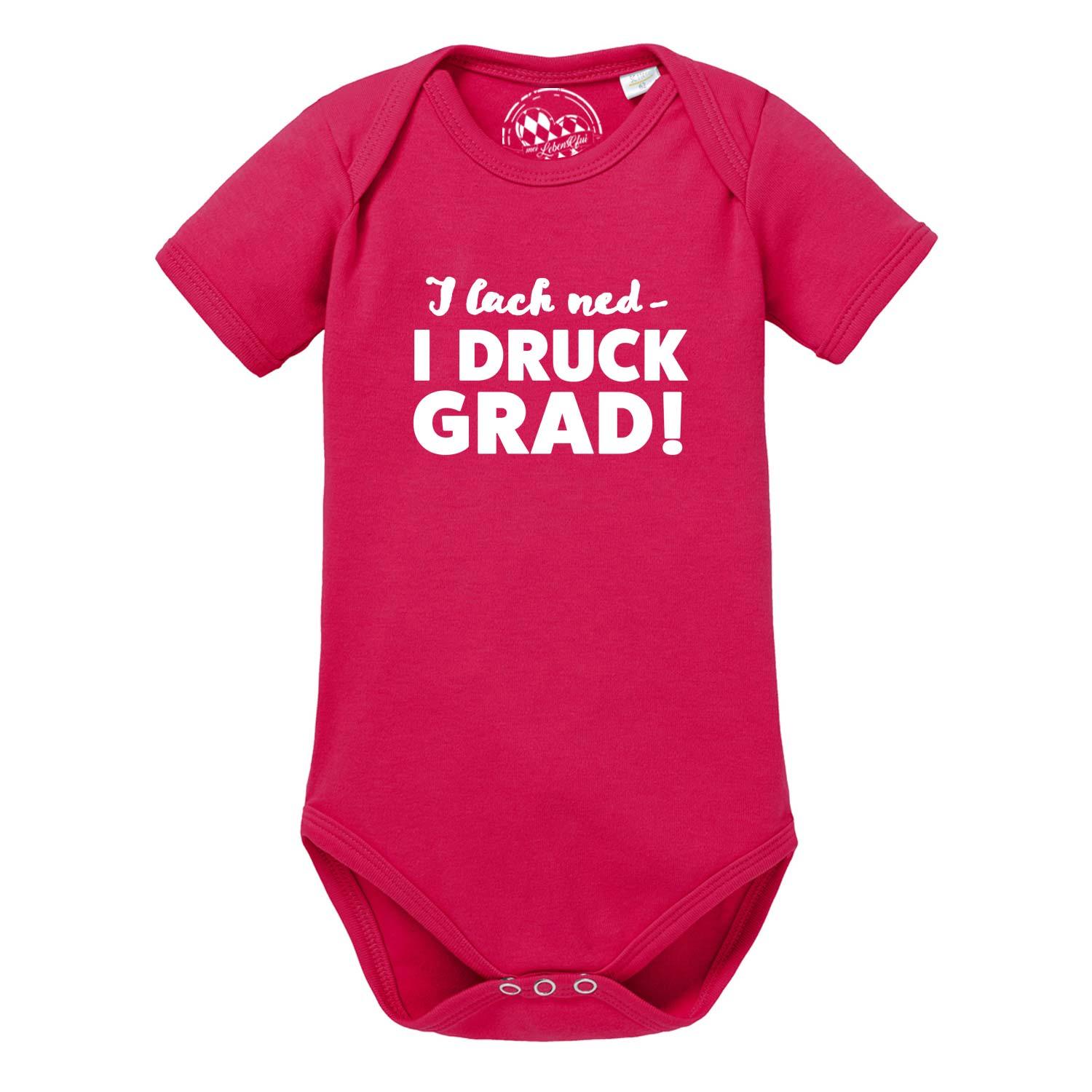 Weißer Babybody mit kurzen Ärmeln und schwarzem Schriftzug „I lach ned…“, Druckknöpfe im Schritt, aus Baumwolle.