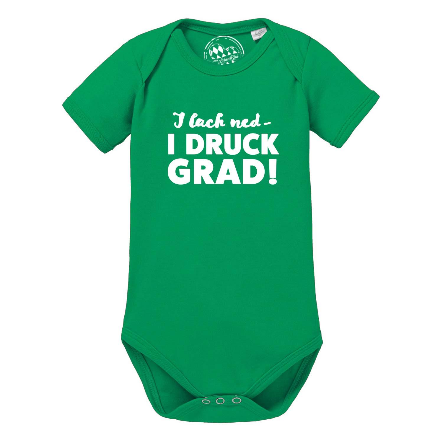 Weißer Baby-Body mit kurzem Arm, schwarzem Aufdruck „I lach ned...“ und Herzsymbol; aus weicher Baumwolle.