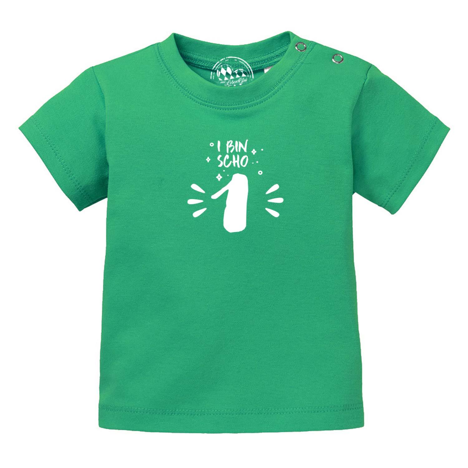 Grünes Baby T-Shirt I bin scho 1 mit weißem Aufdruck und praktischen Druckknöpfen an der Schulter.