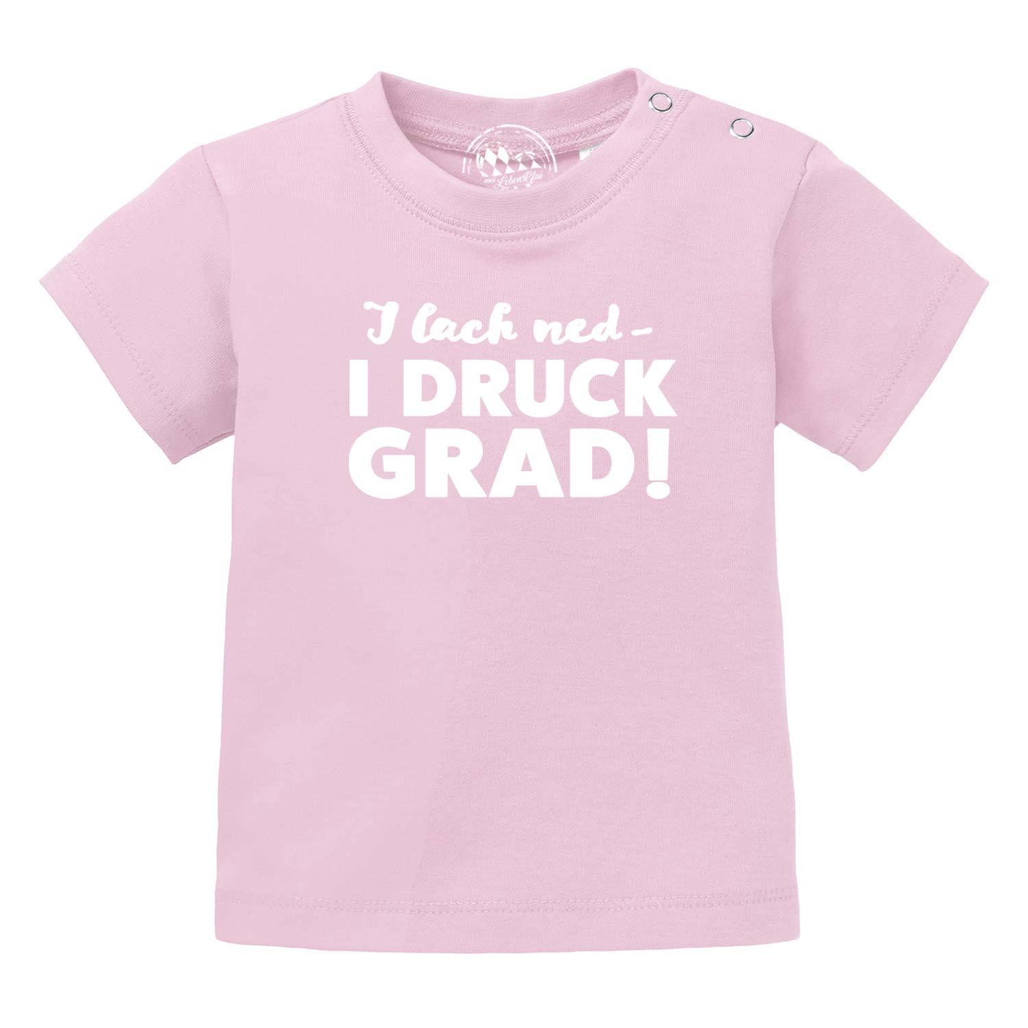 Kurzes Baby-T-Shirt mit Rundhalsausschnitt, rosa, vorn bedruckt mit weißem Schriftzug „I lach ned...“, 100 % Bio-Baumwolle.