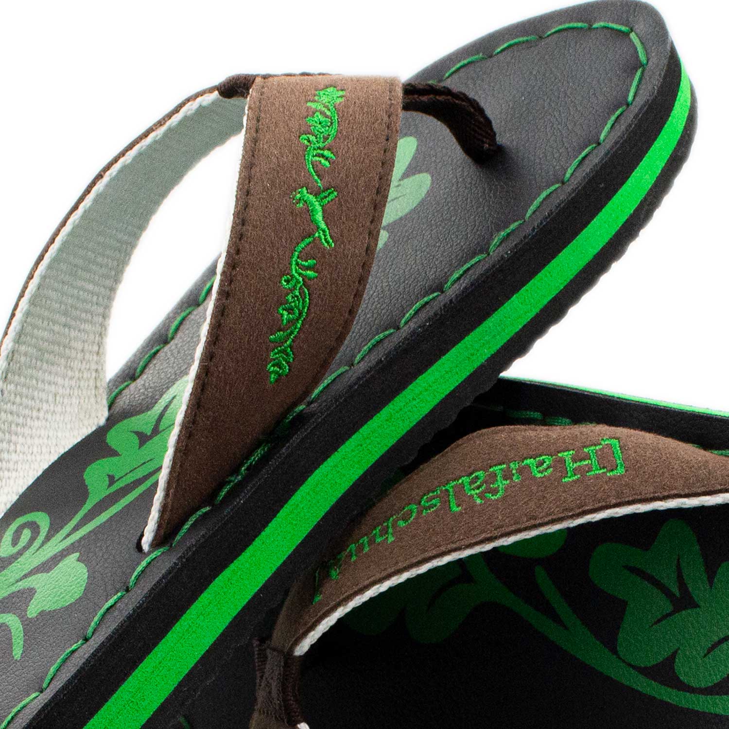 Detailansicht der Badesandale "Haferlschuh" mit braunem Riemen, grüner Stickerei und Sohlenrand.