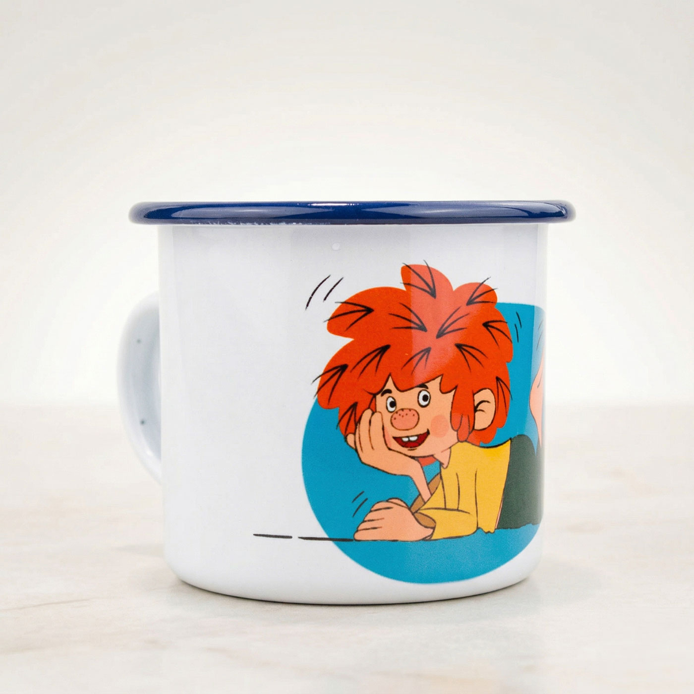 Weiße Emaille-Tasse mit dunkelblauem Rand und Pumuckl-Motiv, der lächelnd auf dem Arm liegt.