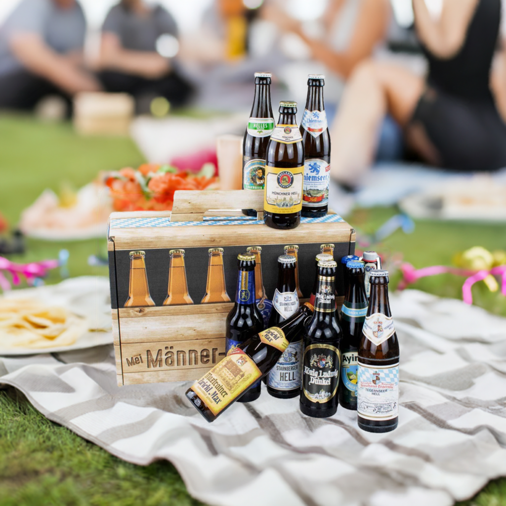 Bier-Geschenk Männer-Handtasche: Holzträger mit vielfältigen Bierflaschen auf einer Picknickdecke im Grünen.
