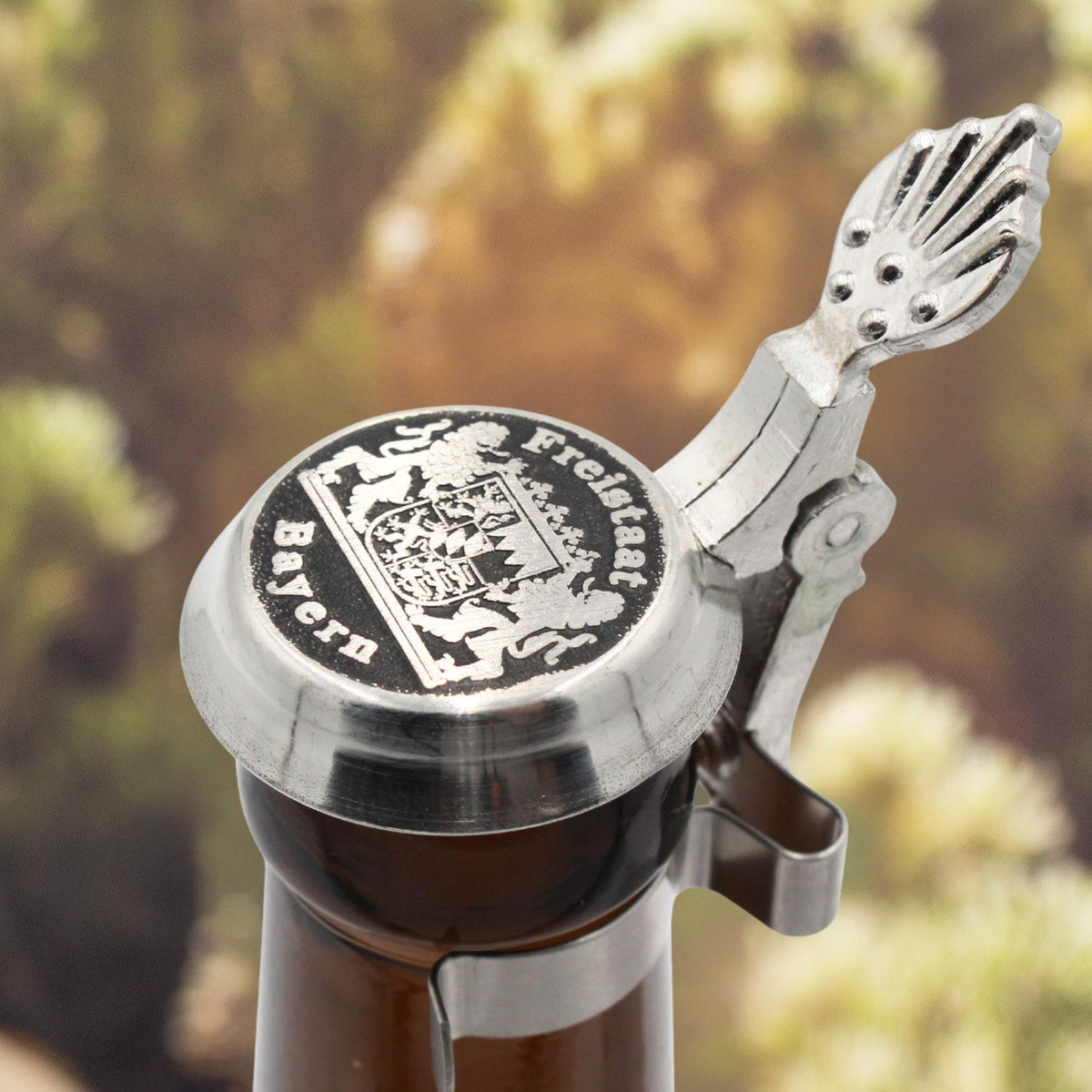 Zinndeckel zum Aufstecken für Bierflaschen mit bayerischem Wappen und Gravur "Freistaat Bayern" auf brauner Flasche.
