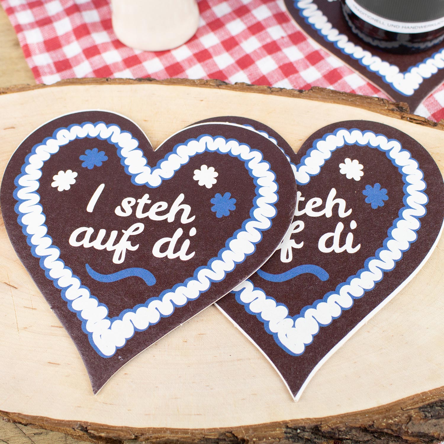Herzförmiger Bierdeckel mit Lebkuchenherz-Motiv und weißem Schriftzug „I steh auf di“, im 20er-Set.