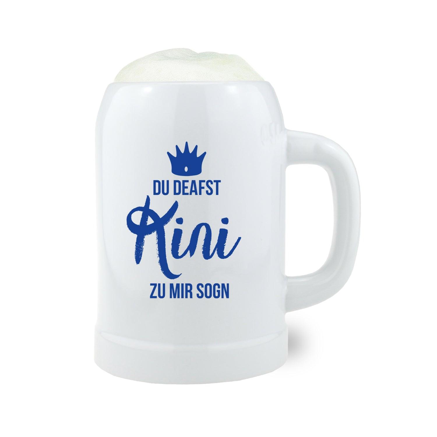 Steinkrug mit Henkel und blauem Schriftzug „Du deafst Kini zu mir sogn“ auf naturgrauem, mattiertem Keramikmaterial, 0,5 L.