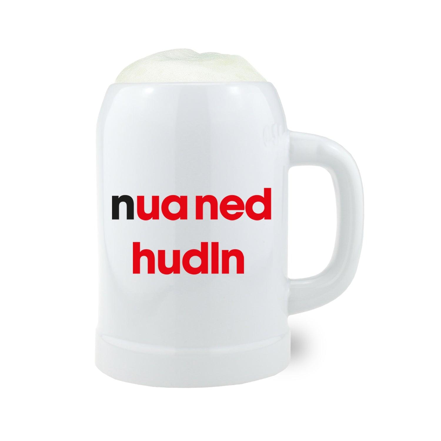 Halbhoher Bierkrug aus Steinzeug mit Henkel, bayrischem Schriftzug „Nua ned hudln“, ca. 0,5 l, grau-beige.
