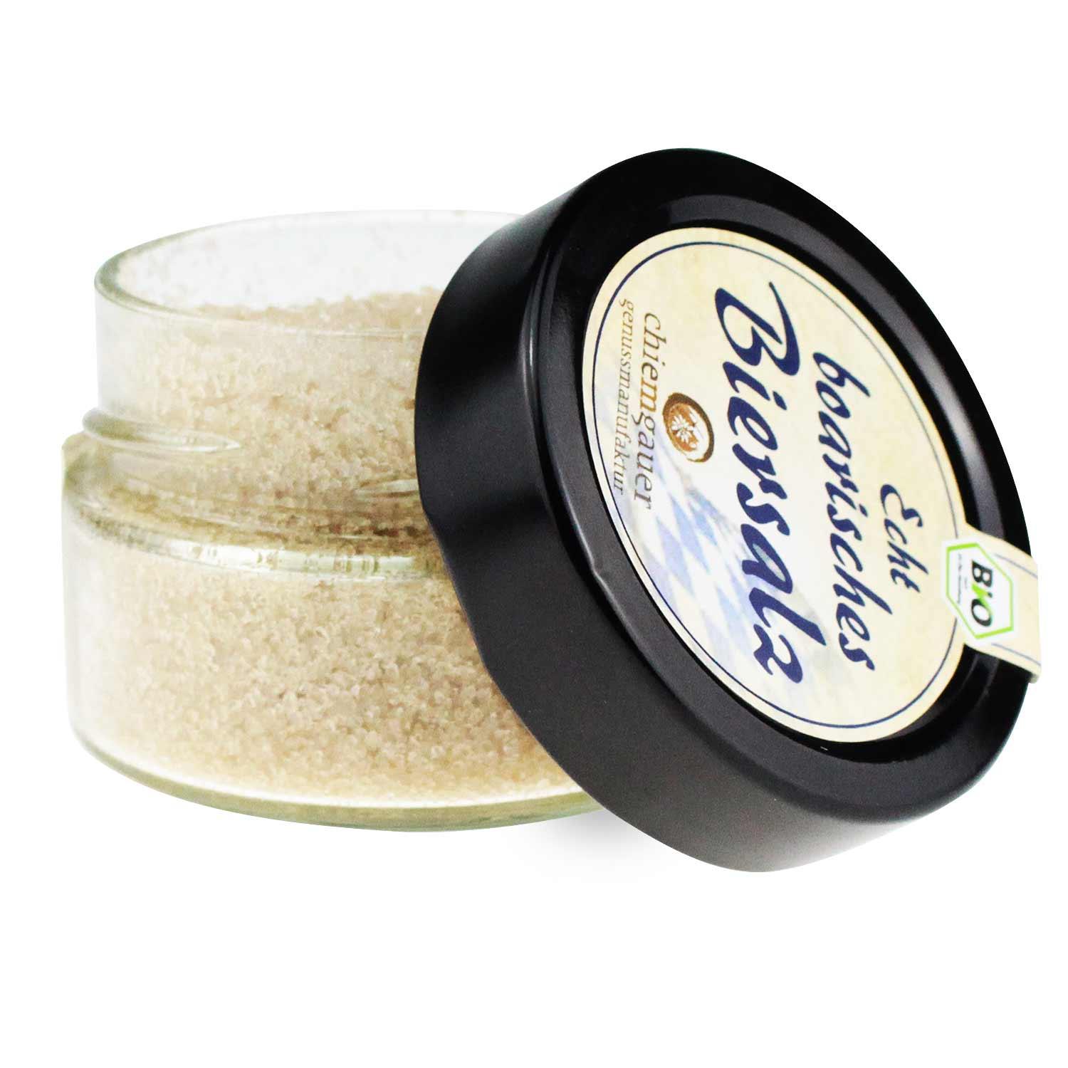 Grobes Biersalz mit brauner Färbung, sichtbaren Kräutern und Gewürzen in Glasröhre mit Korkverschluss.