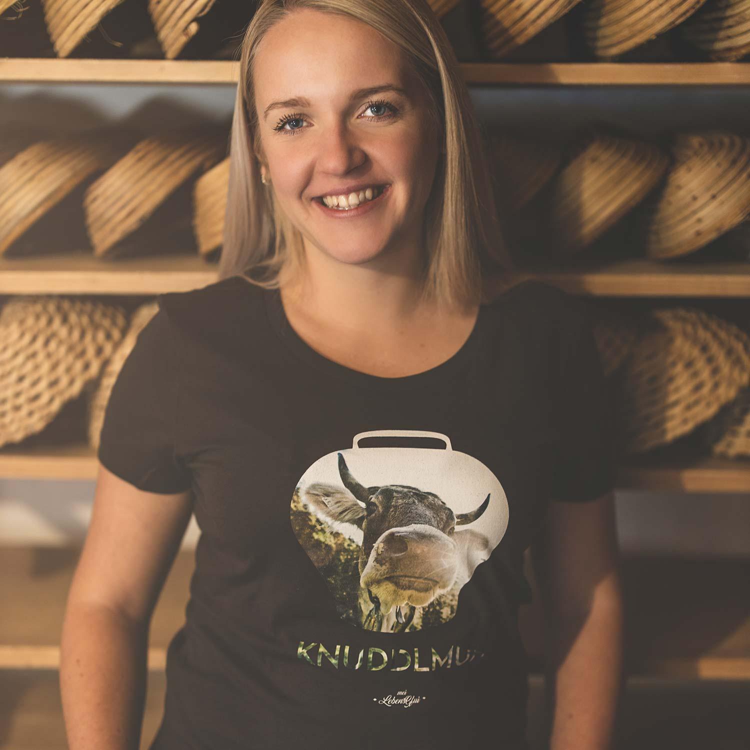 Damen T-Shirt in Dunkelgrau mit weißem Kuh-Motiv und Schriftzug „Knuddlmuh“, aus 100 % Bio-Baumwolle.