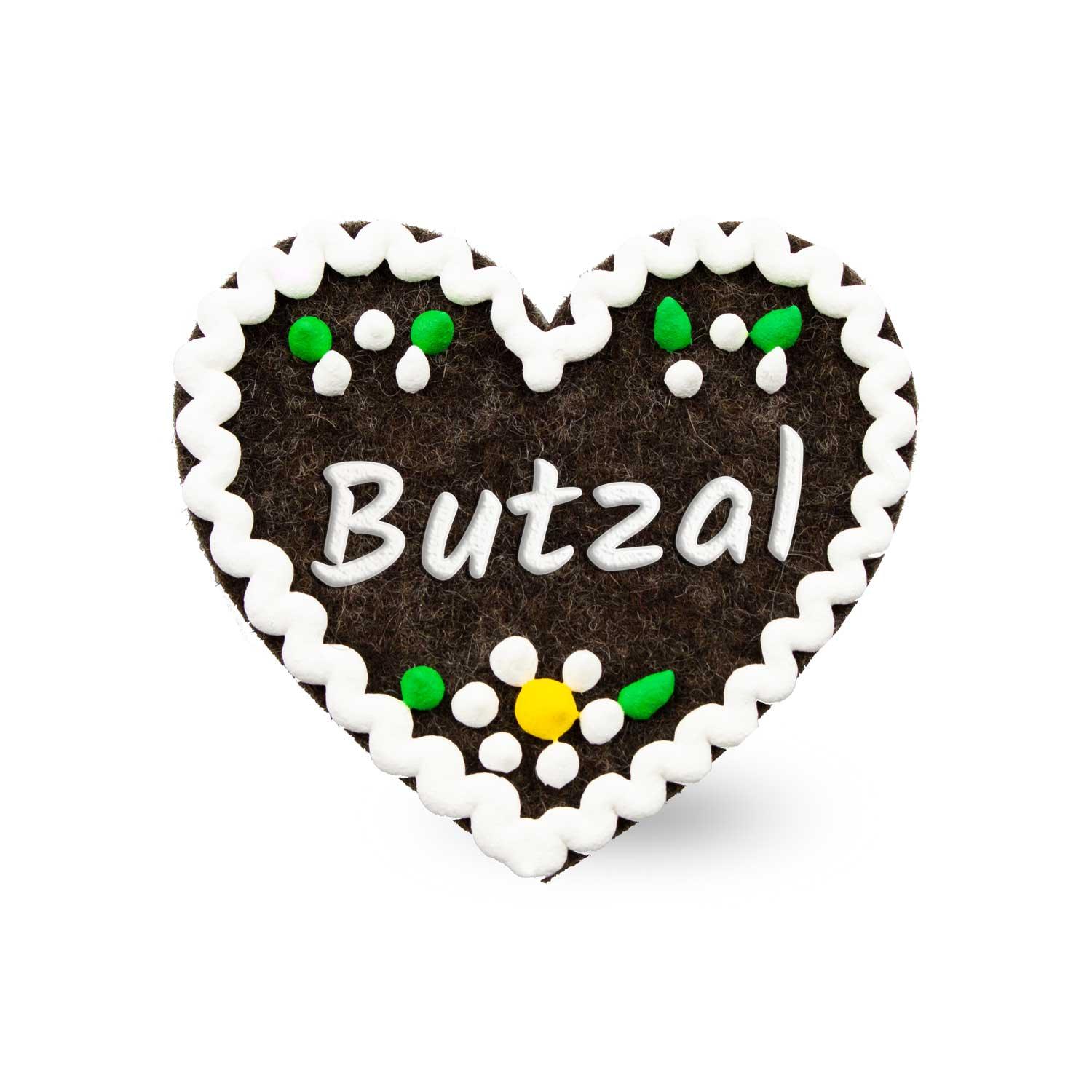 Herzförmiger Filz-Anstecker mit aufgesticktem Schriftzug „Butzal“, Sicherheitsverschluss auf der Rückseite; ca. 6,5 x 7 cm.
