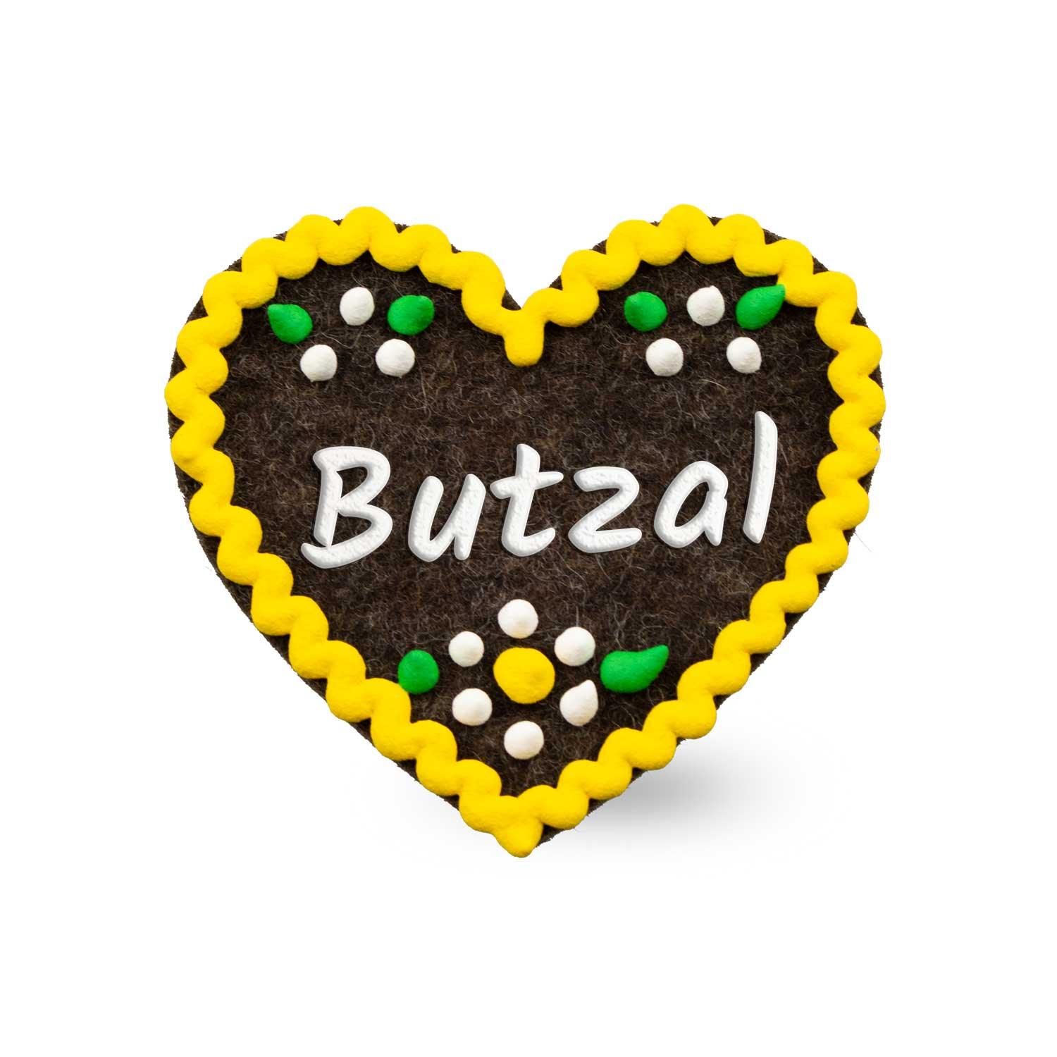 Herzförmiger Filz-Anstecker mit aufgenähtem Schriftzug „Butzal“ und Sicherheitsverschluss auf der Rückseite, ca. 6,5 x 7 cm.