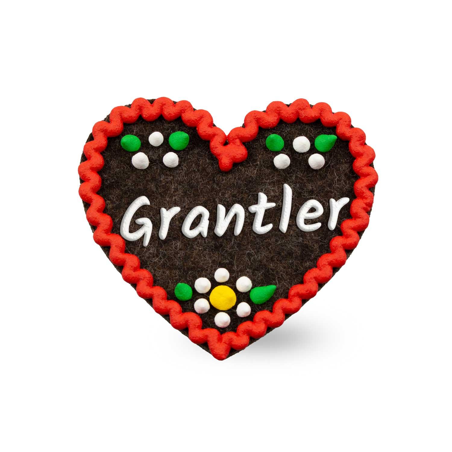 Herzförmiger Filz-Anstecker mit aufgesticktem Schriftzug "Grantler" und Sicherheitsverschluss auf der Rückseite, ca. 6,5 x 7 cm.