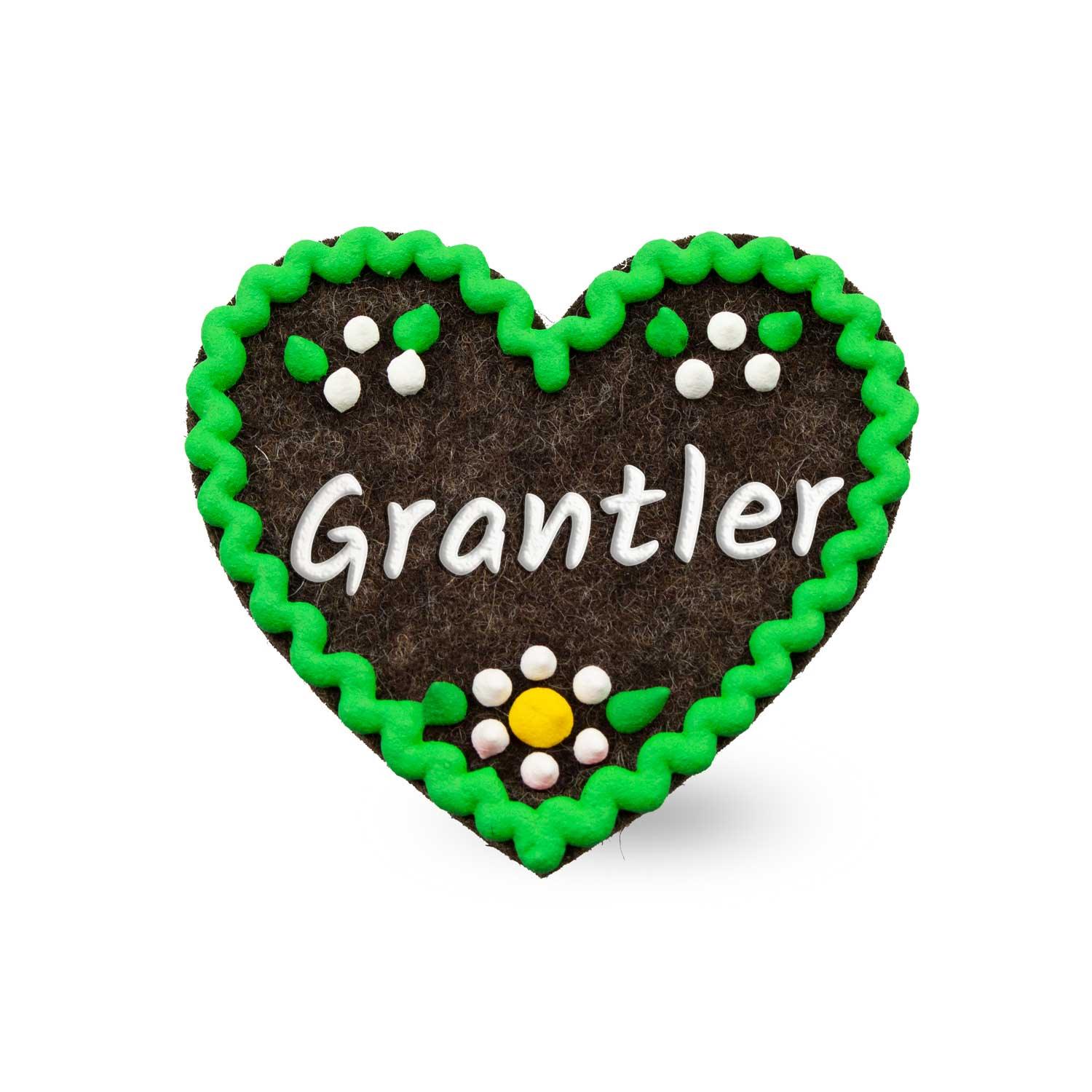Herzförmiger Filz-Anstecker mit aufgesticktem Schriftzug „Grantler“ und Sicherheitsverschluss auf der Rückseite, ca. 6,5 x 7 cm.