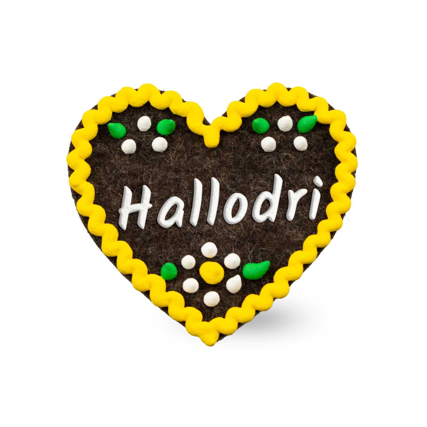 Herzförmiger Anstecker aus Filz mit gesticktem Schriftzug „Hallodri“, Sicherheitsverschluss auf der Rückseite; ca. 6,5 x 7 cm.