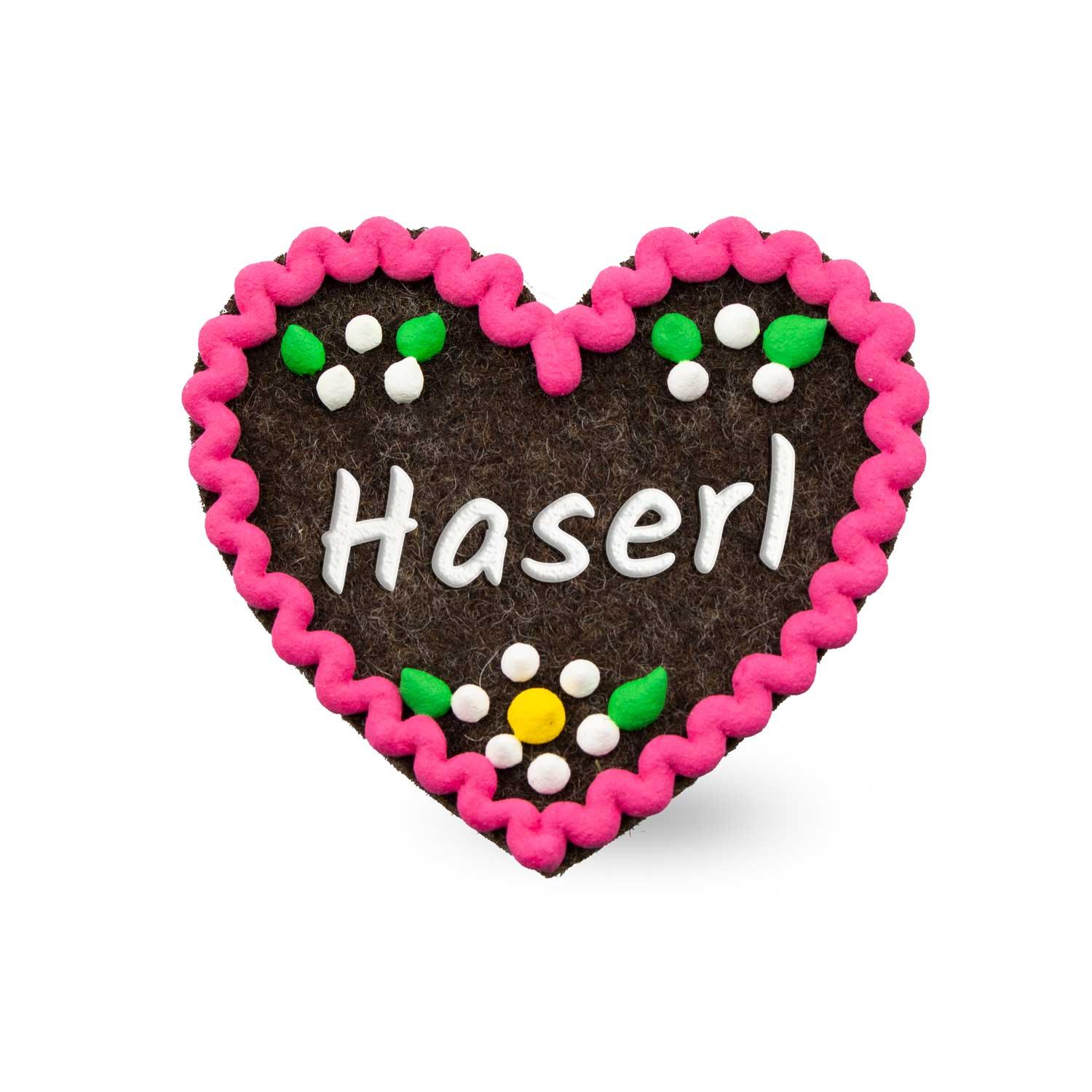 Herzförmiger Filz-Anstecker mit gesticktem Schriftzug „Haserl“ und Sicherheitsverschluss auf der Rückseite, ca. 6,5 x 7 cm.