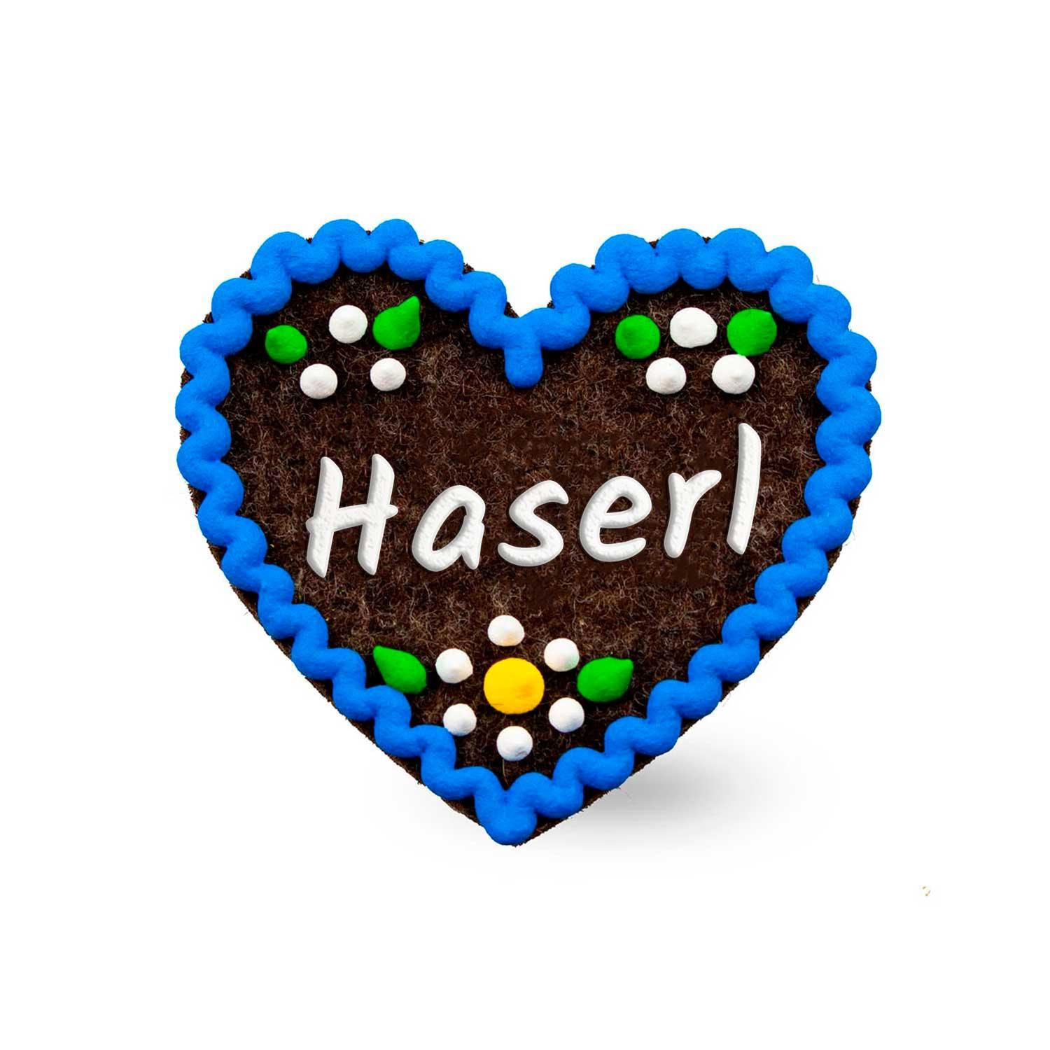 Herzförmiger Filz-Anstecker mit gesticktem Schriftzug „Haserl“ und dekorativem Zierband; ca. 6,5 x 7 cm.