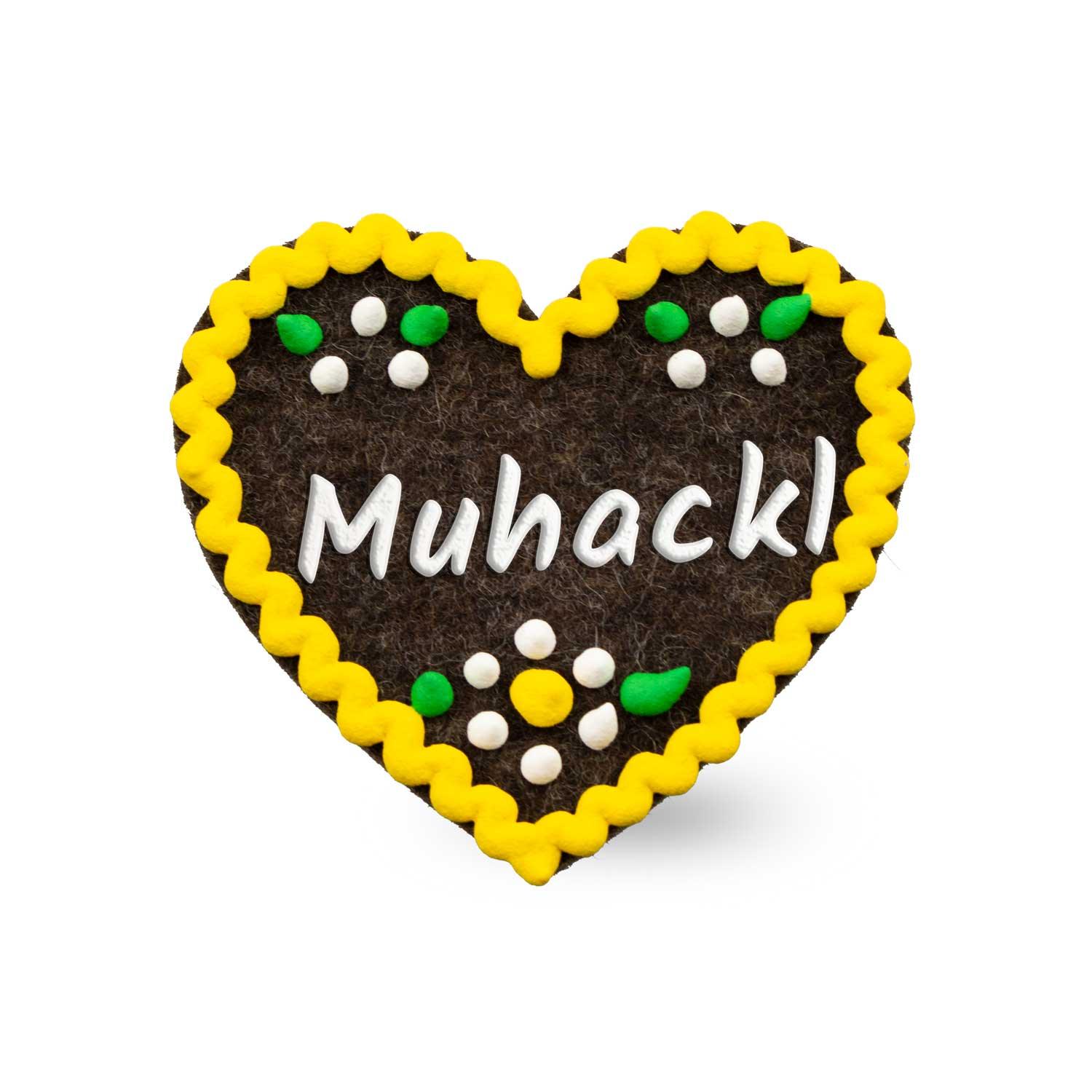 Herzförmiger Filz-Anstecker mit gesticktem Schriftzug „Muhackl“ und Sicherheitsverschluss auf der Rückseite, ca. 6,5 x 7 cm.
