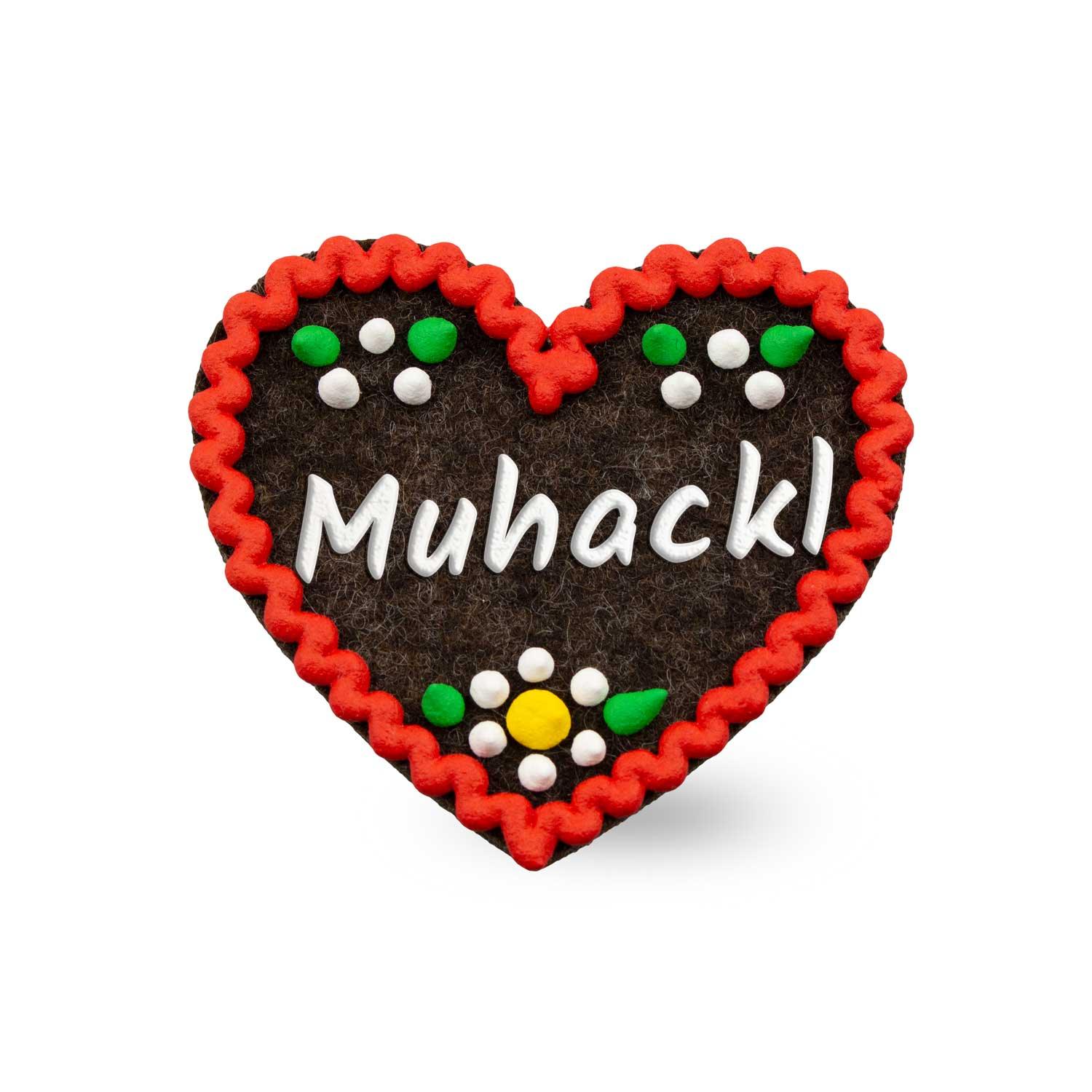 Herzförmiger Filz-Anstecker mit gesticktem „Muhackl“-Schriftzug und Sicherheitsverschluss auf der Rückseite; ca. 6,5 x 7 cm.
