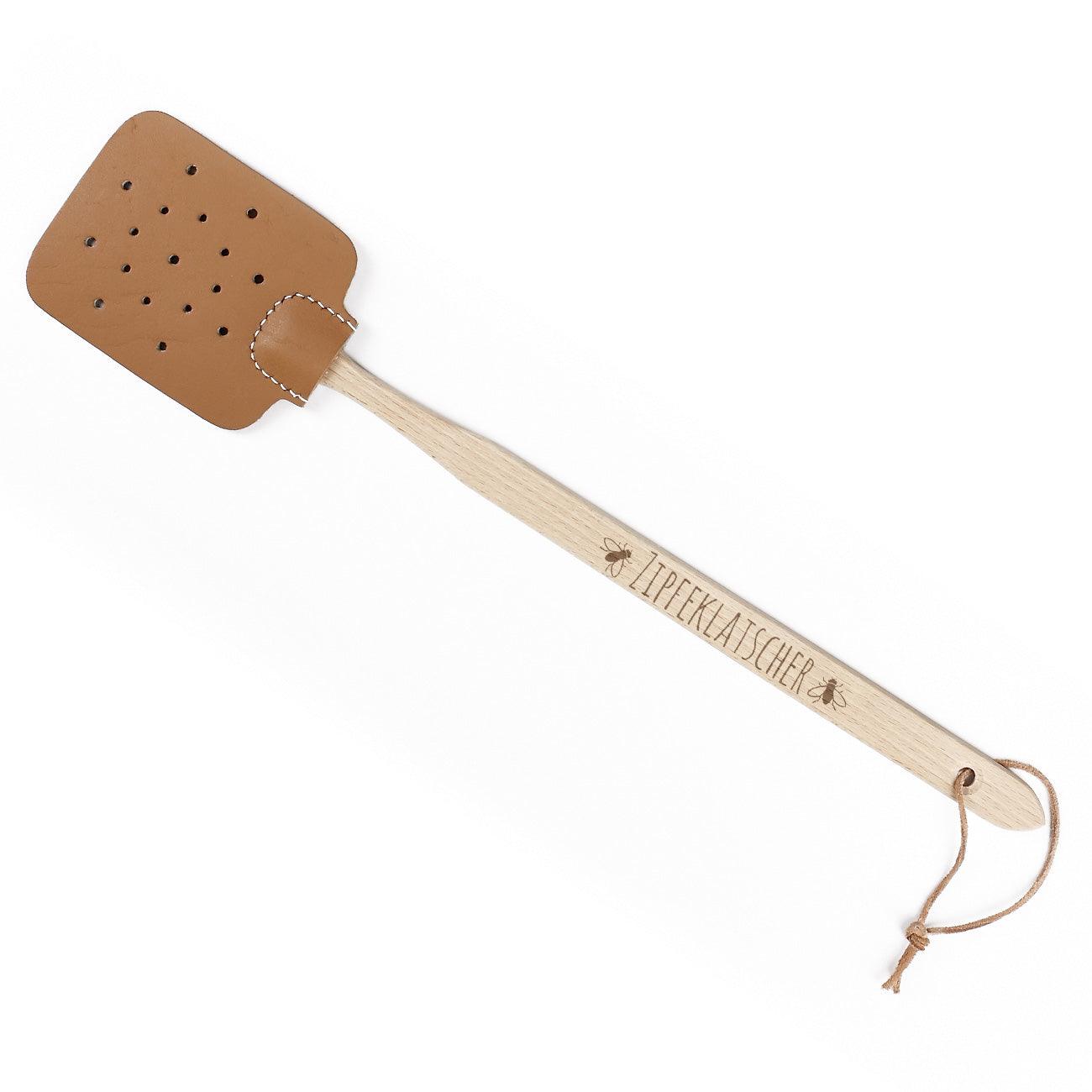 Fliegenklatsche aus Holz mit breiter Lederfläche, darauf weißer Schriftzug „Zipfeklatscher“ im Retro-Stil.