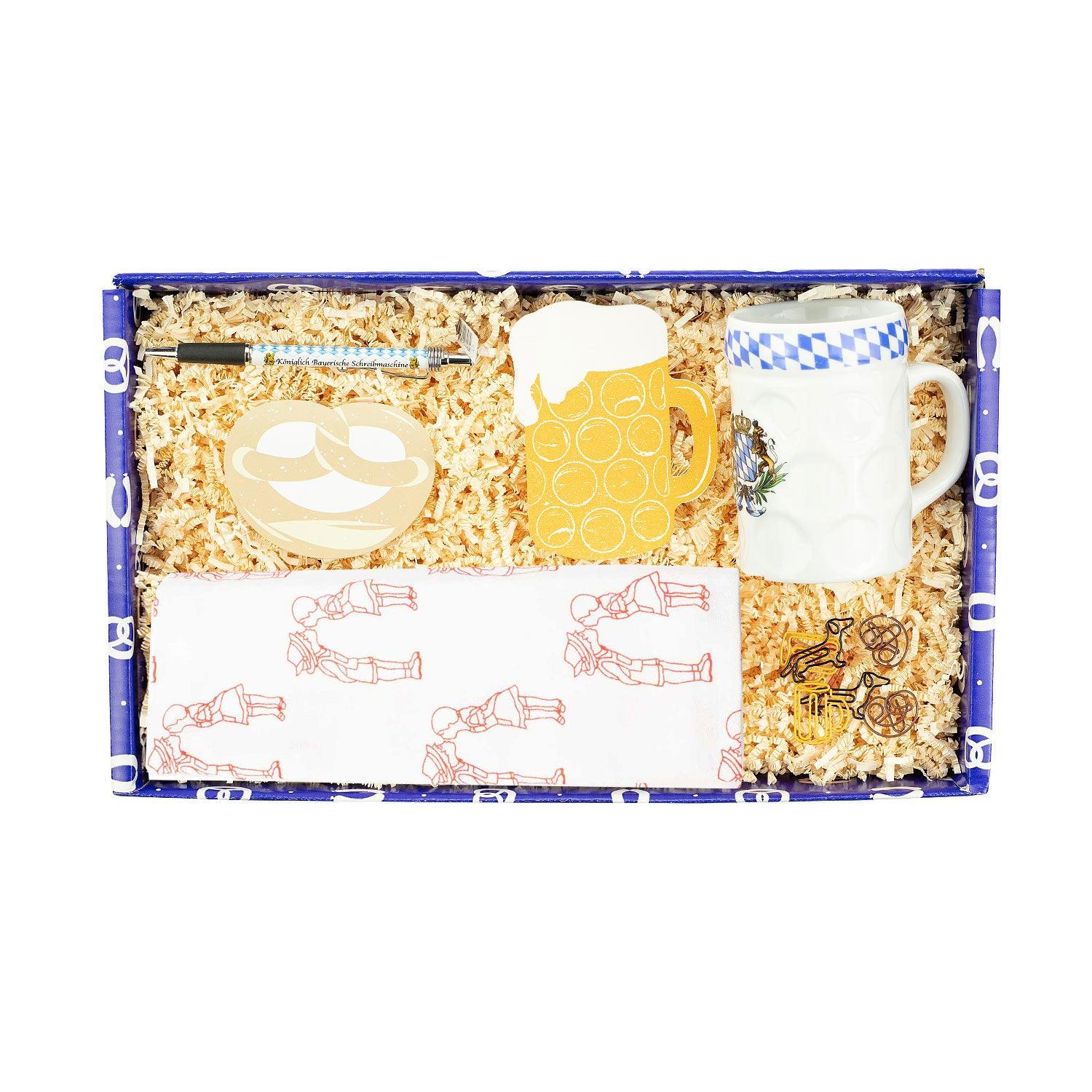 Geschenkbox mit Emaille-Tasse, Geschirrtuch mit Herzmotiv, Notizzettel, Schwamm, Kugelschreiber und Büroklammern.