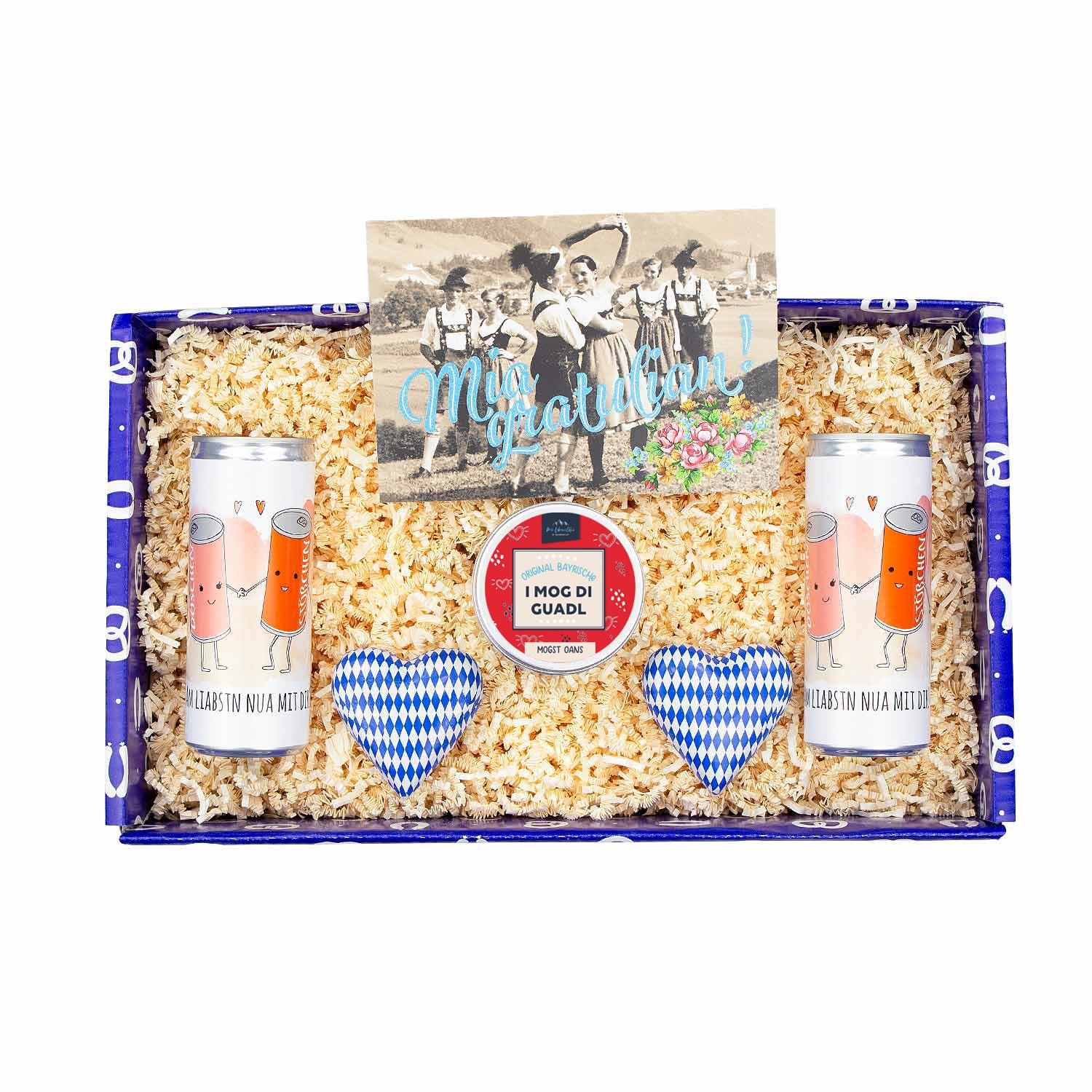 Geschenkbox mit zwei gold-roten Secco-Dosen, Herz-Bonbons, Grußkarte „Mia gratulian!“ mit Glitzerdruck, rechteckig.