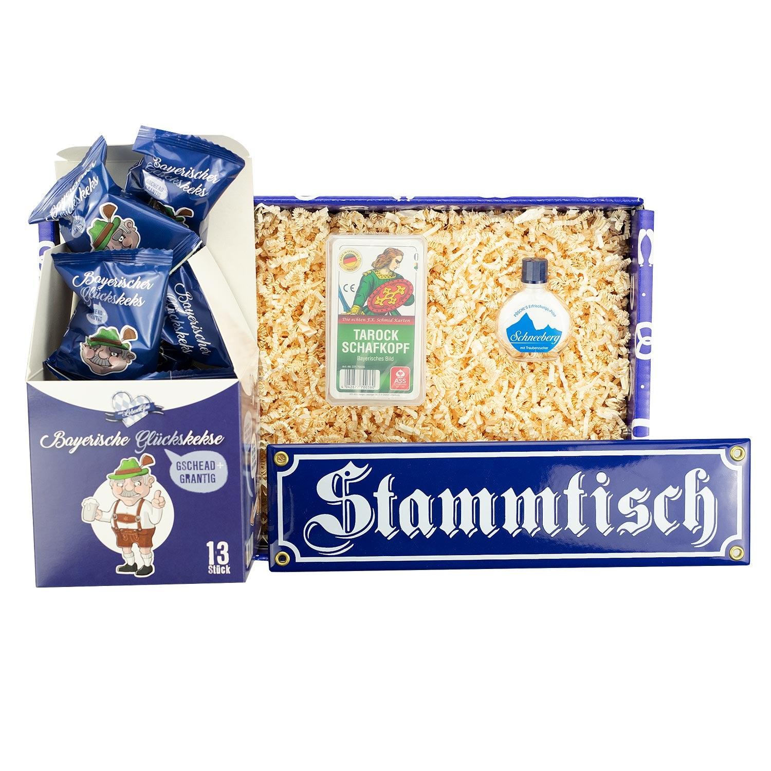 Bayerische Geschenkbox mit Emaille-Schild „Stammtisch“, Schafkopfkarten und Keks mit Grantler-Gesicht, bunt sortiert.