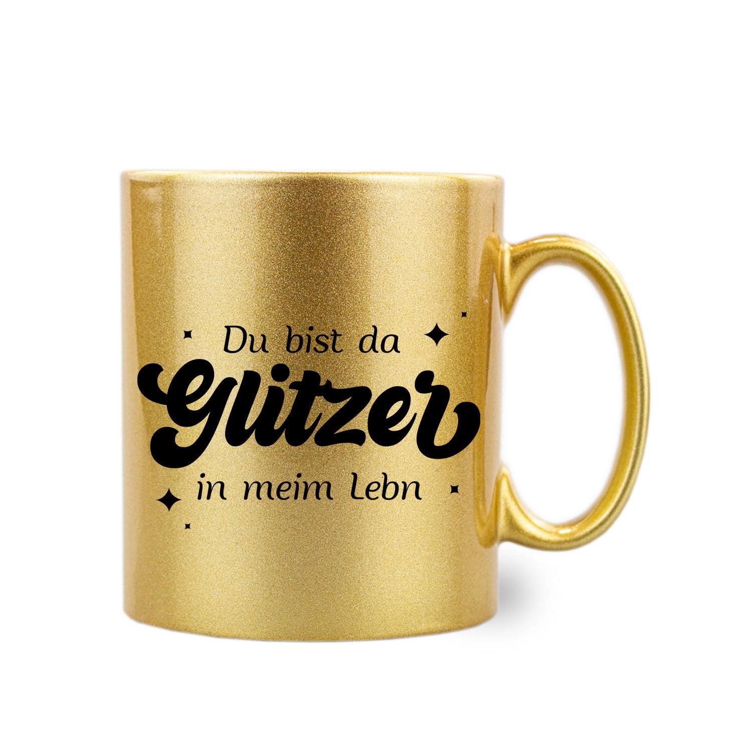 Gold-glitzernde Keramiktasse mit geschwungenem Henkel und Schriftzug „Du bist da Glitzer in meim Lebn“, ca. 300 ml.
