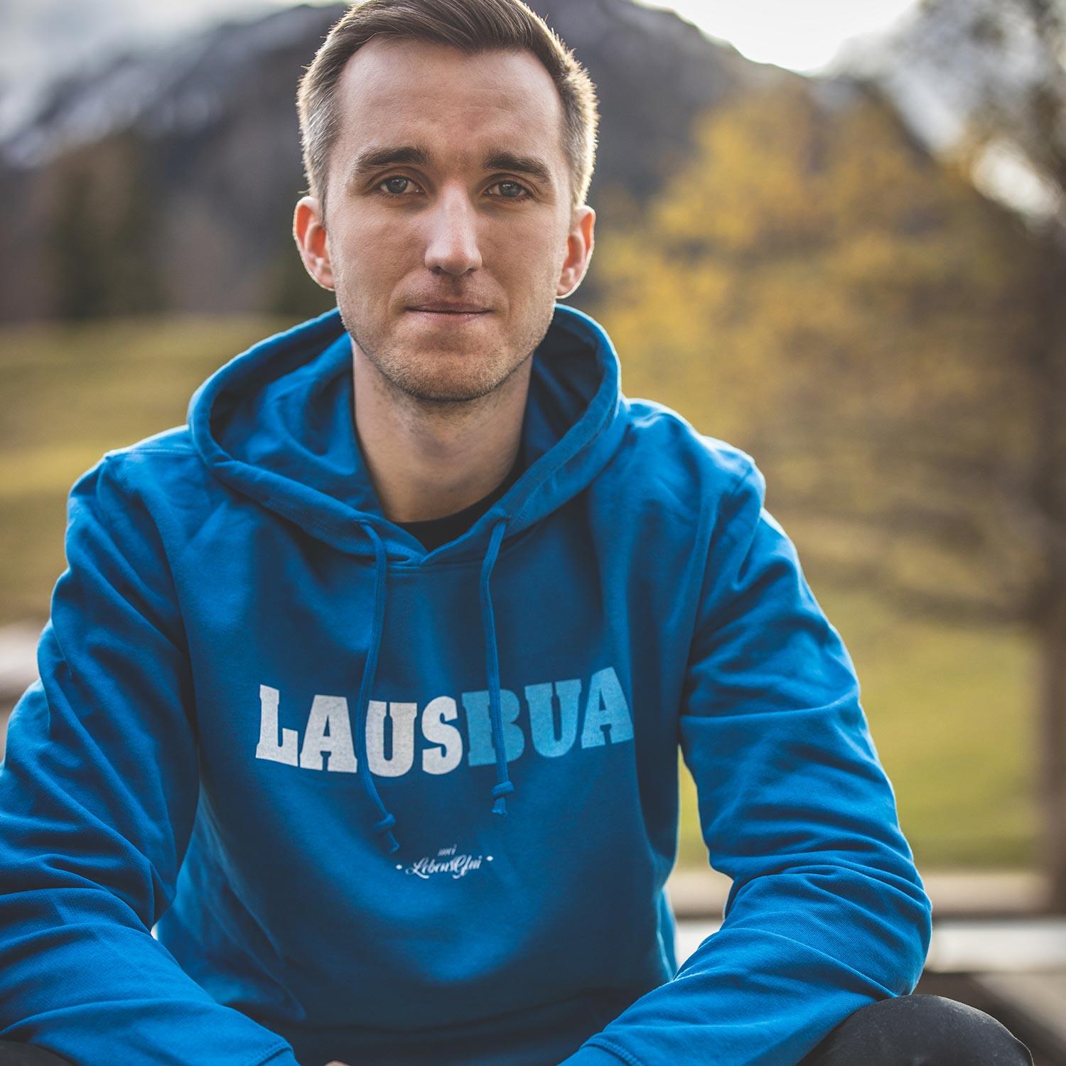 Dunkelblauer Herren-Hoodie mit weißem "Lausbua"-Schriftzug auf der Brust, Kapuze, Kängurutasche; Bio-Baumwolle.