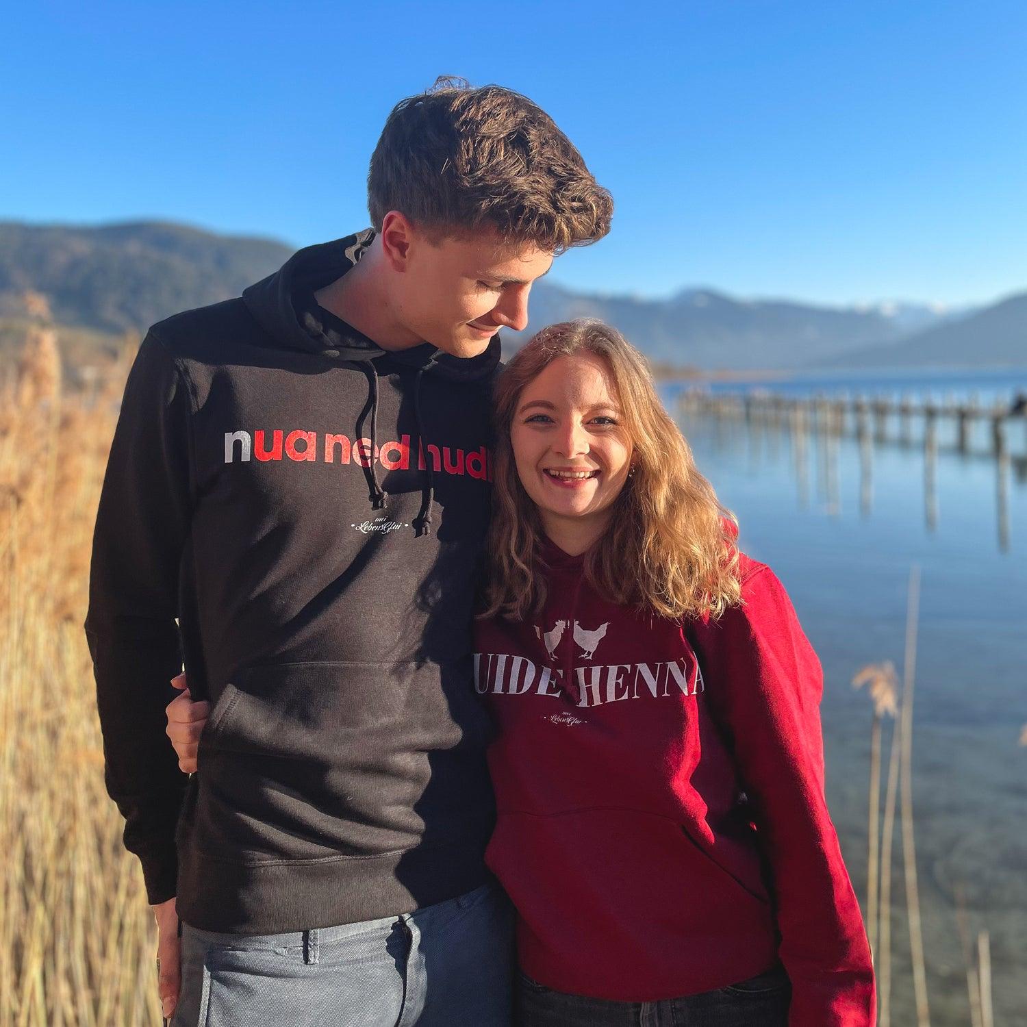 Grauer Herren-Hoodie mit Kapuze, Fronttasche und weißem Aufdruck „nua ned hudln“ in bayerischer Mundart; Bio-Baumwolle, recyceltes Polyester.