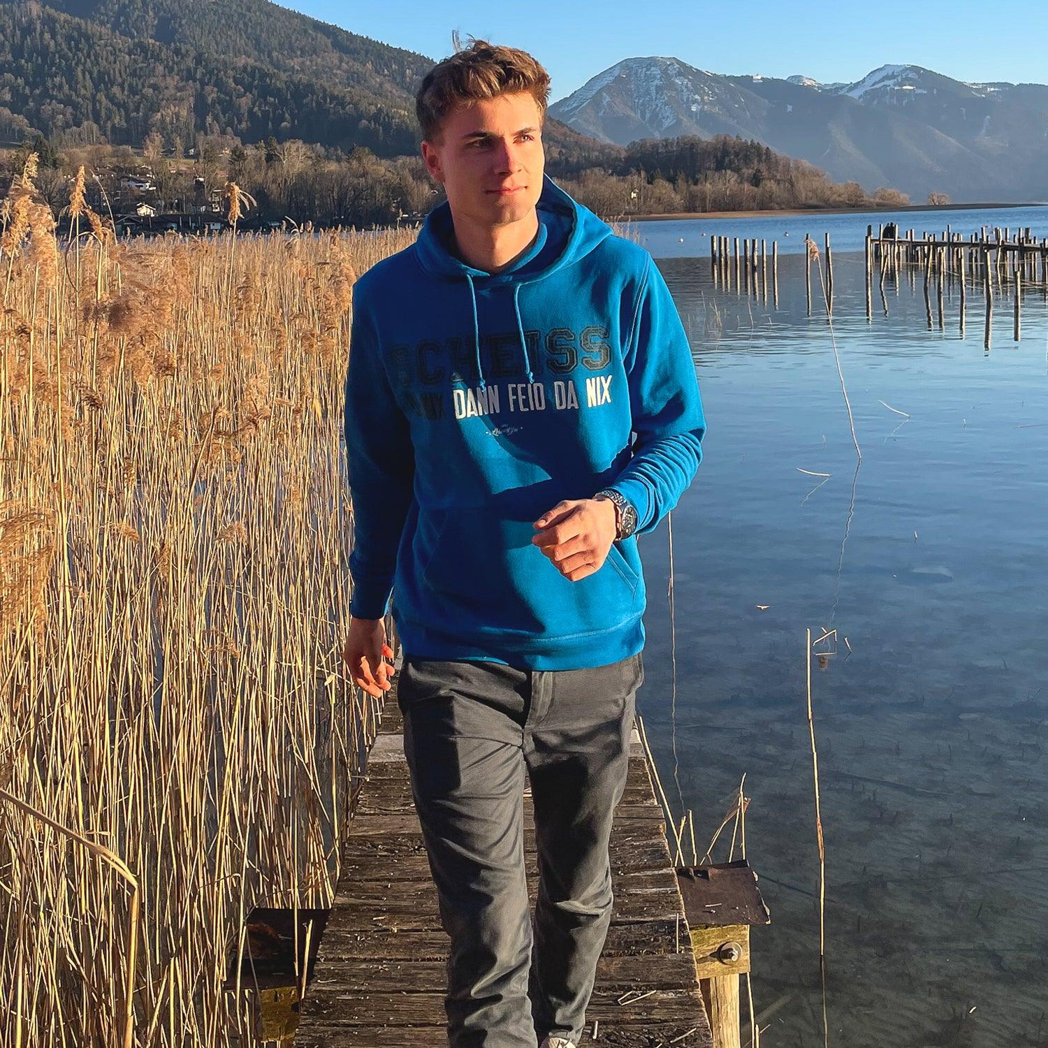 Dunkelblauer Herren-Hoodie mit weißem Frontprint „Scheiß da nix“, Kapuze und Kängurutasche; Bio-Baumwolle-Mix.