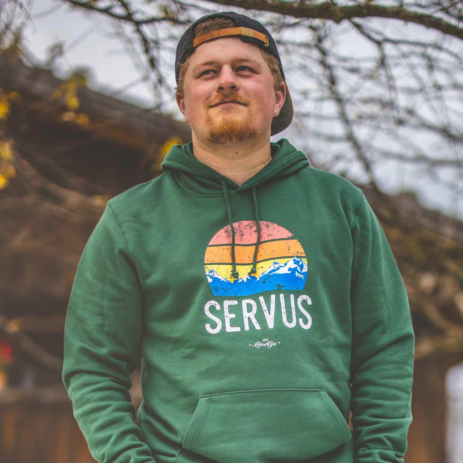 Grauer Herren Hoodie mit weißem „Servus“-Schriftzug, Kapuze und Kängurutasche aus Bio-Baumwolle und Recycling-Polyester.