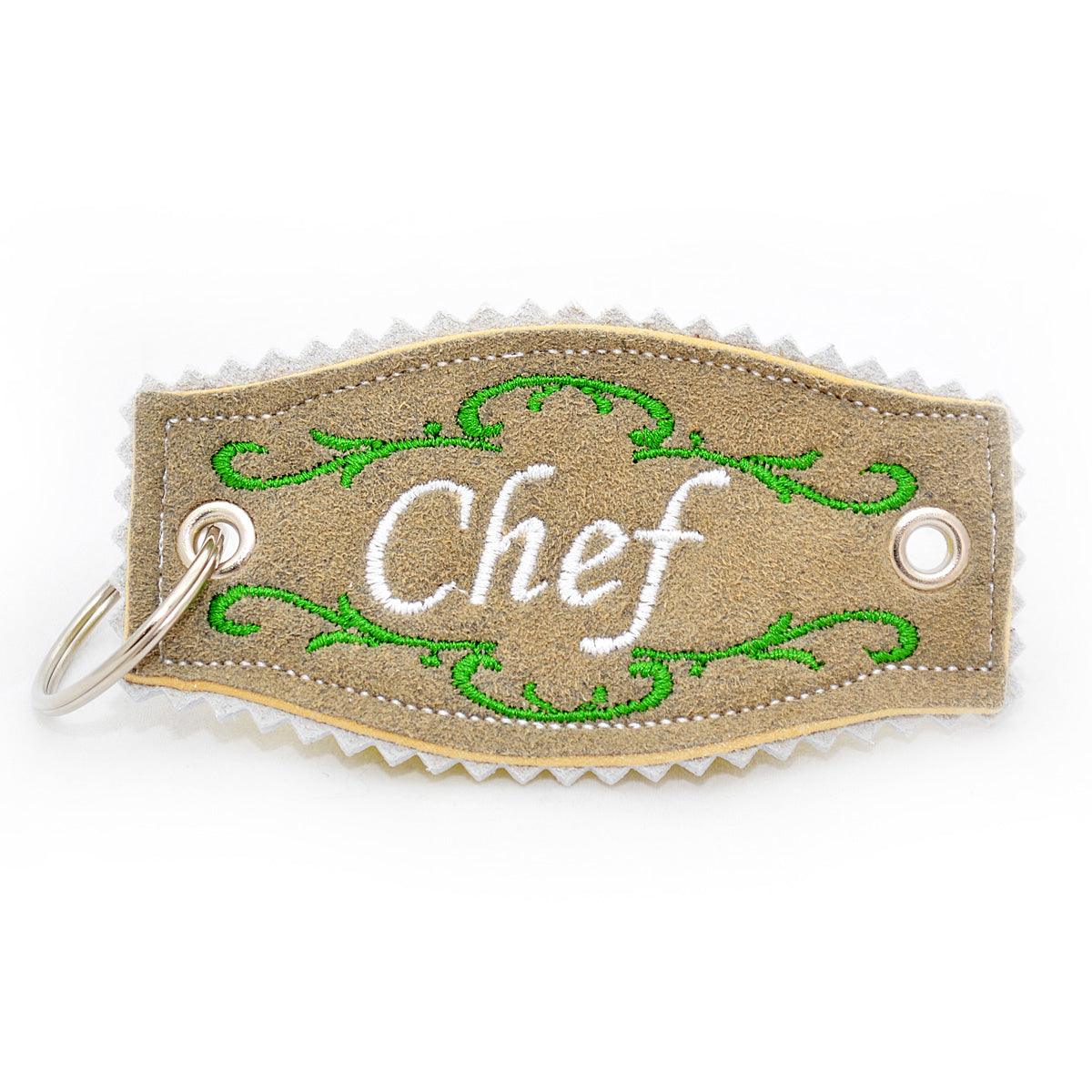 Brauner Leder-Schlüsselanhänger mit weißer "Chef" Stickerei und grünen Blumenranken, Metallring.