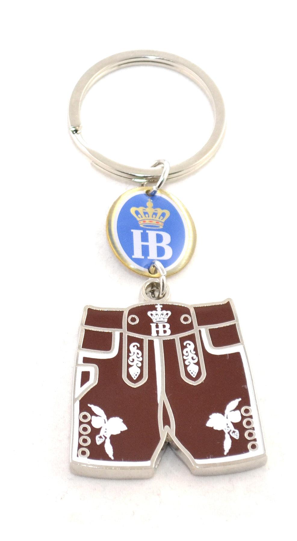 Metall-Schlüsselanhänger in Lederhosenform mit bayerischem Muster, Hirschmotiv und blauem Schriftzug „Hofbräu“.
