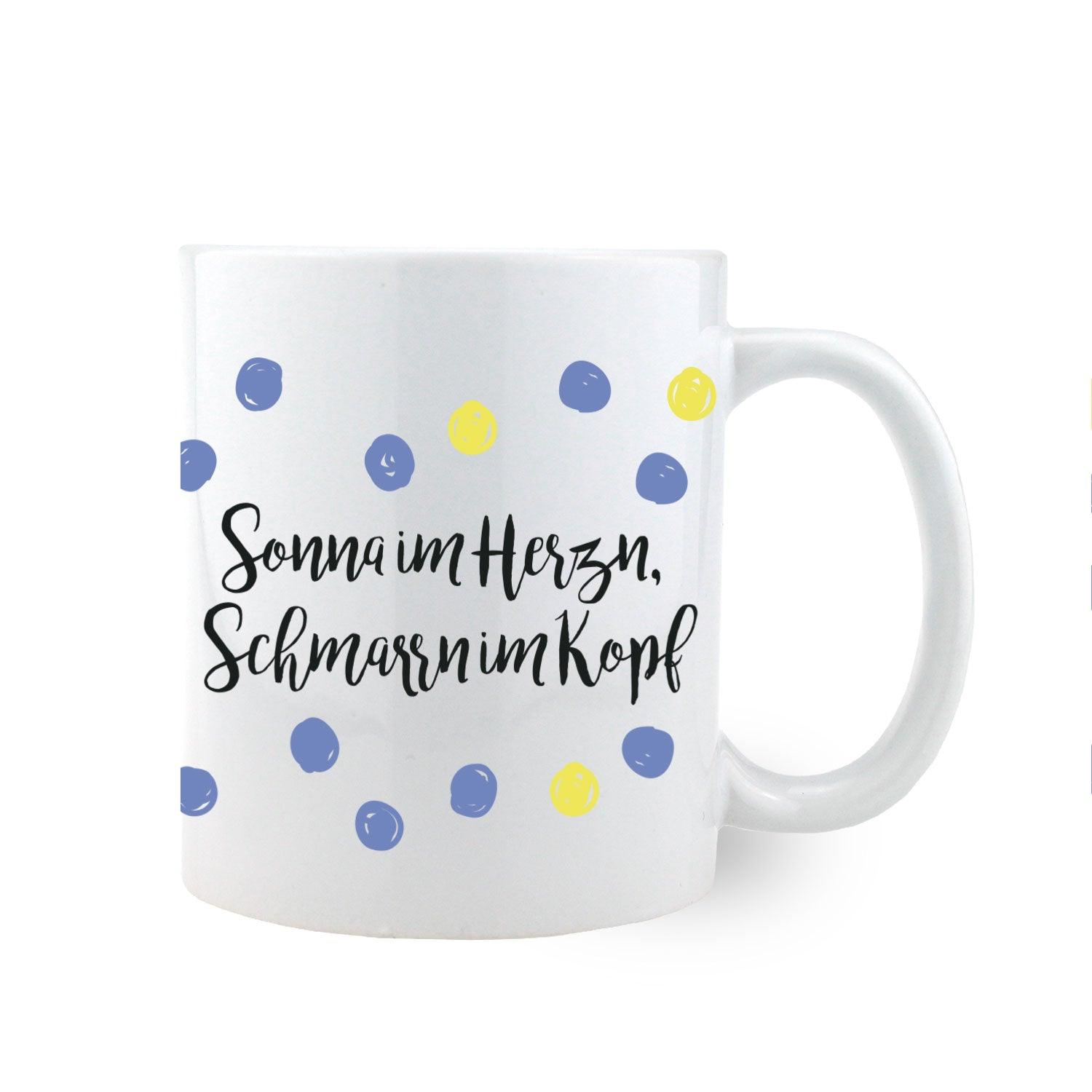 Keramiktasse mit rundem Henkel, Aufdruck „Sonna im Herzn, Schmarrn im Kopf“, ca. 330 ml, spülmaschinengeeignet.