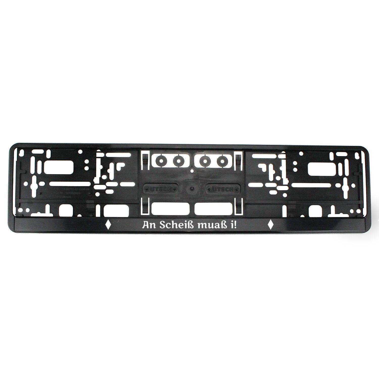 Schwarzer Kennzeichenhalter mit weißem Schriftzug „An Scheiß muaß i!“, rechteckige Form, witterungsbeständig.