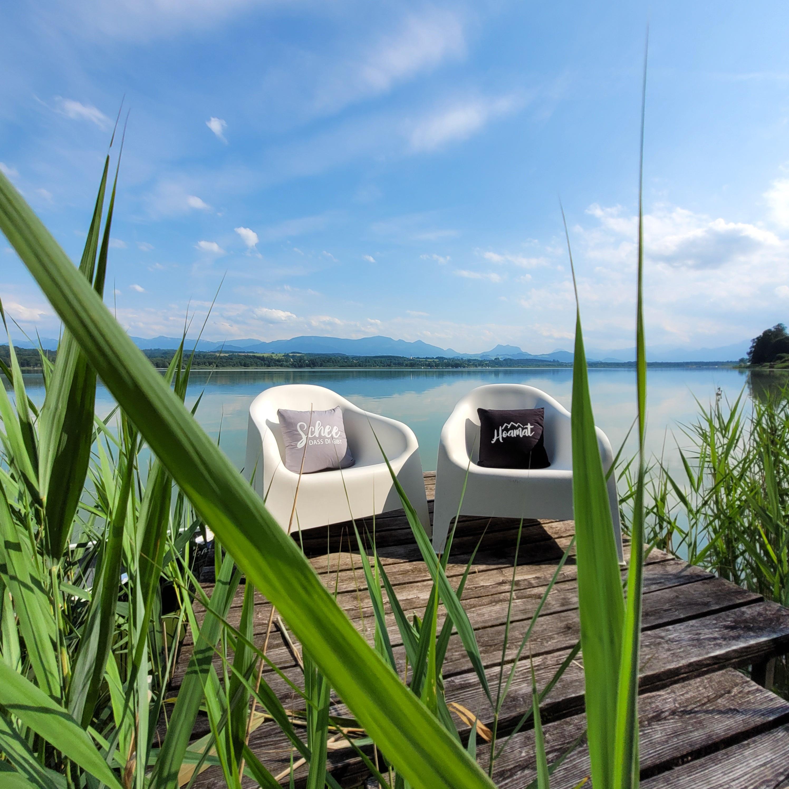 Quadratisches Dekokissen mit bayerischem Schriftzug „Hoamat“ in Herzform, aus Baumwolle, ca. 40 x 40 cm.