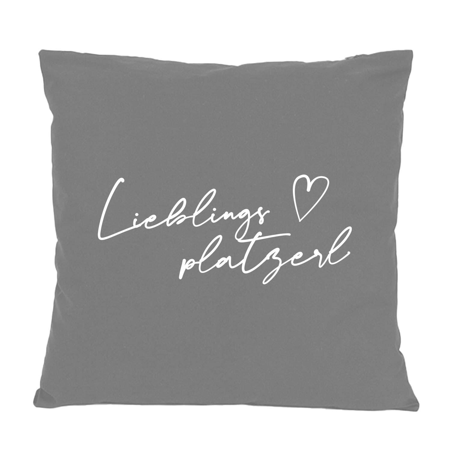 Quadratisches Dekokissen mit Herz-Motiv und bayerischem Schriftzug „Lieblingsplatzerl“, aus 100 % Baumwolle, 40×40 cm.